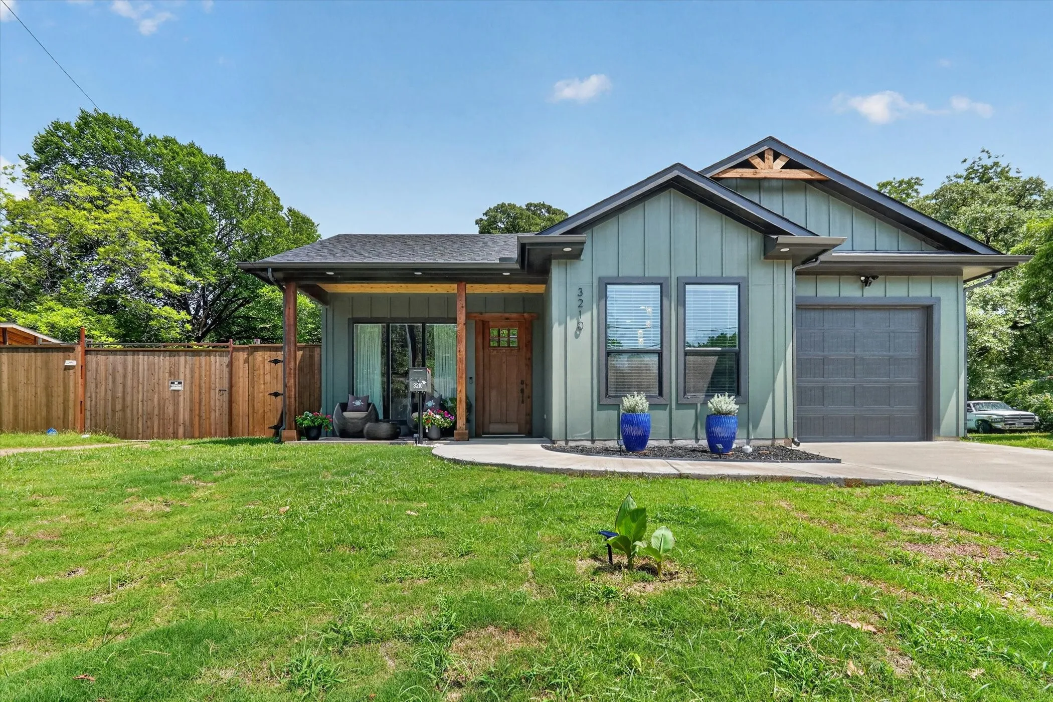 Modern exterior featuring board and batten siding, a covered front porch, and a wood privacy fence