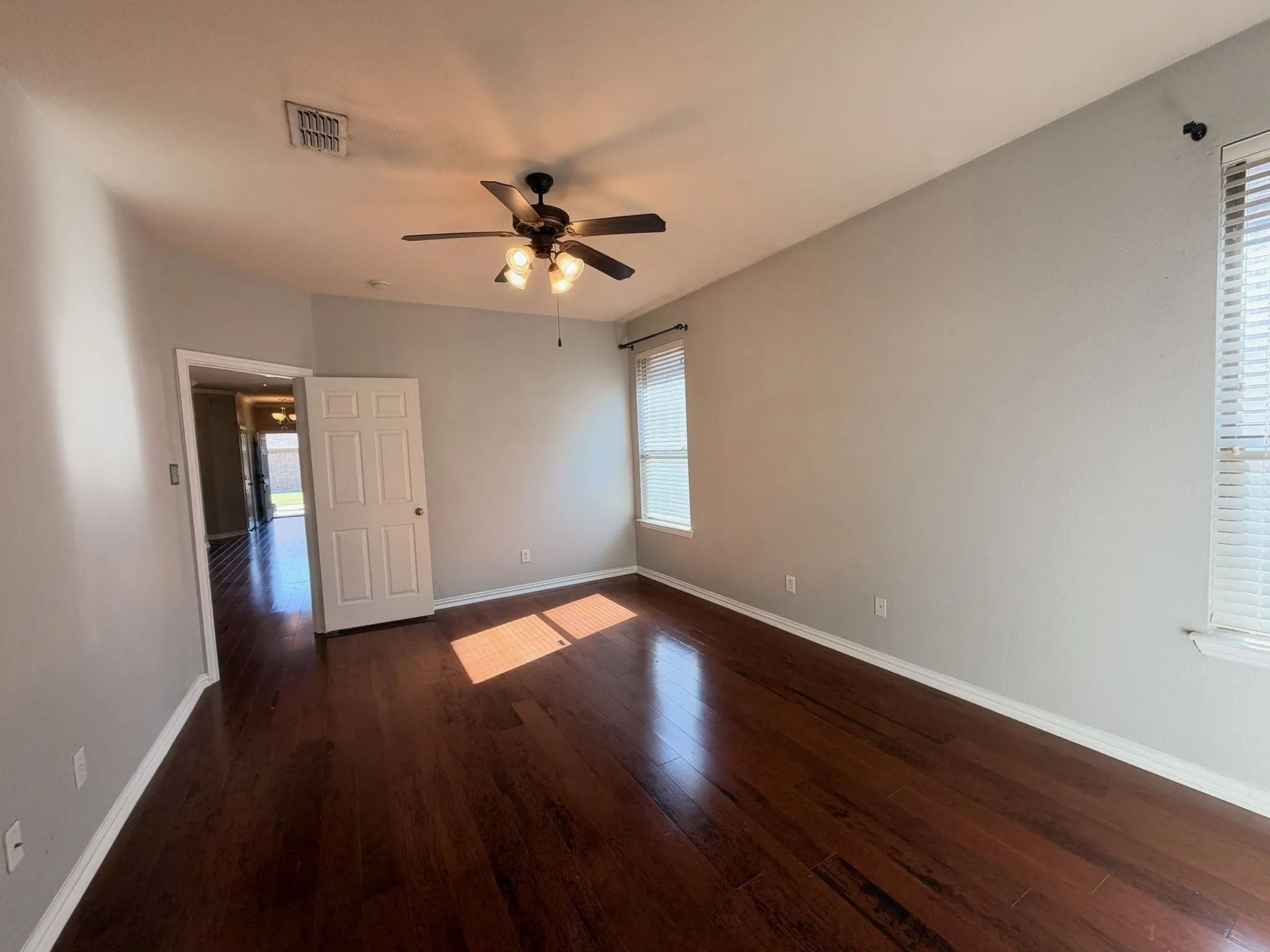 Wood-finish flooring, ceiling fan with integrated lighting, and multiple windows