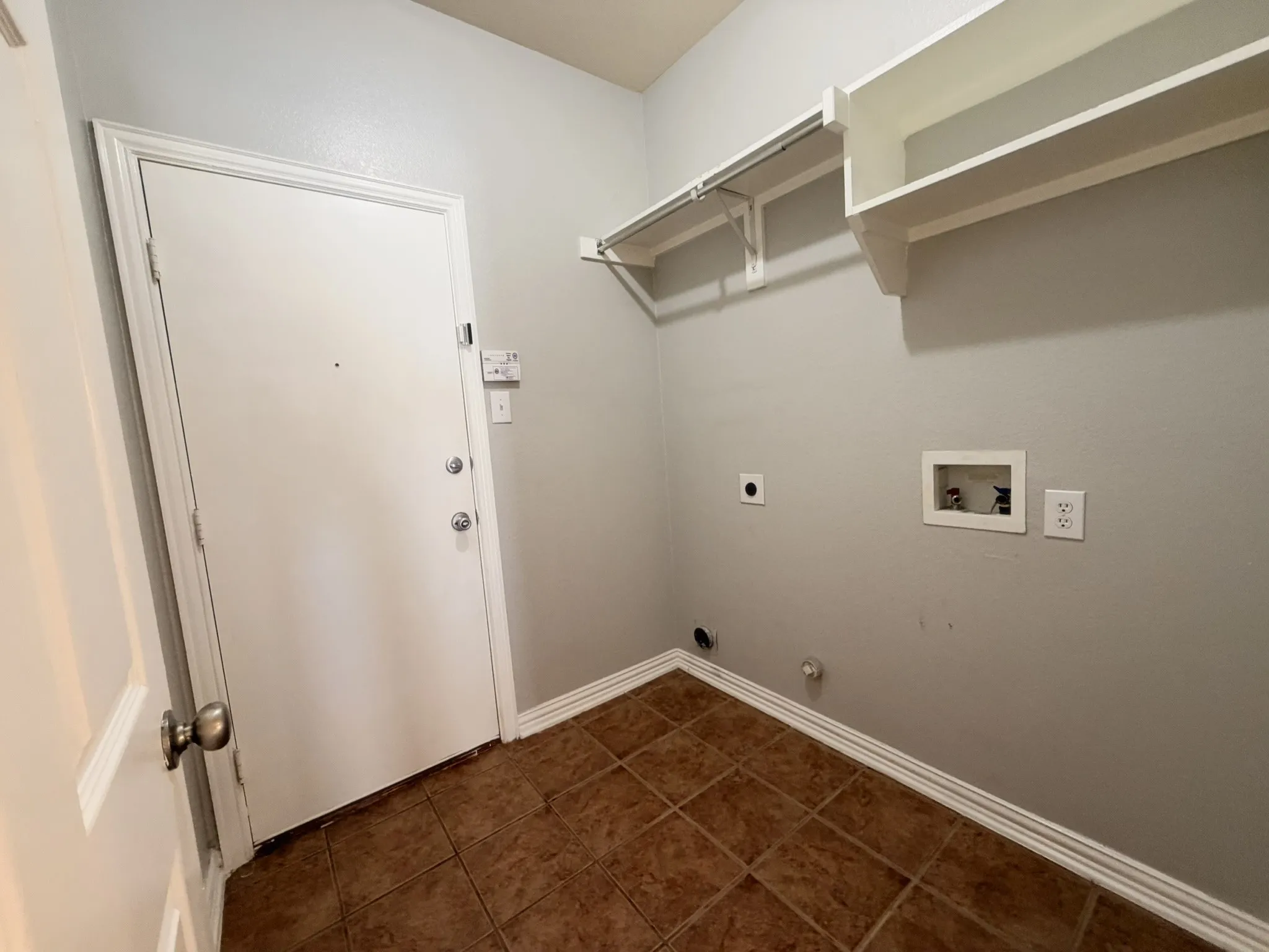 Utility area featuring tile flooring, white walls, and built-in shelving