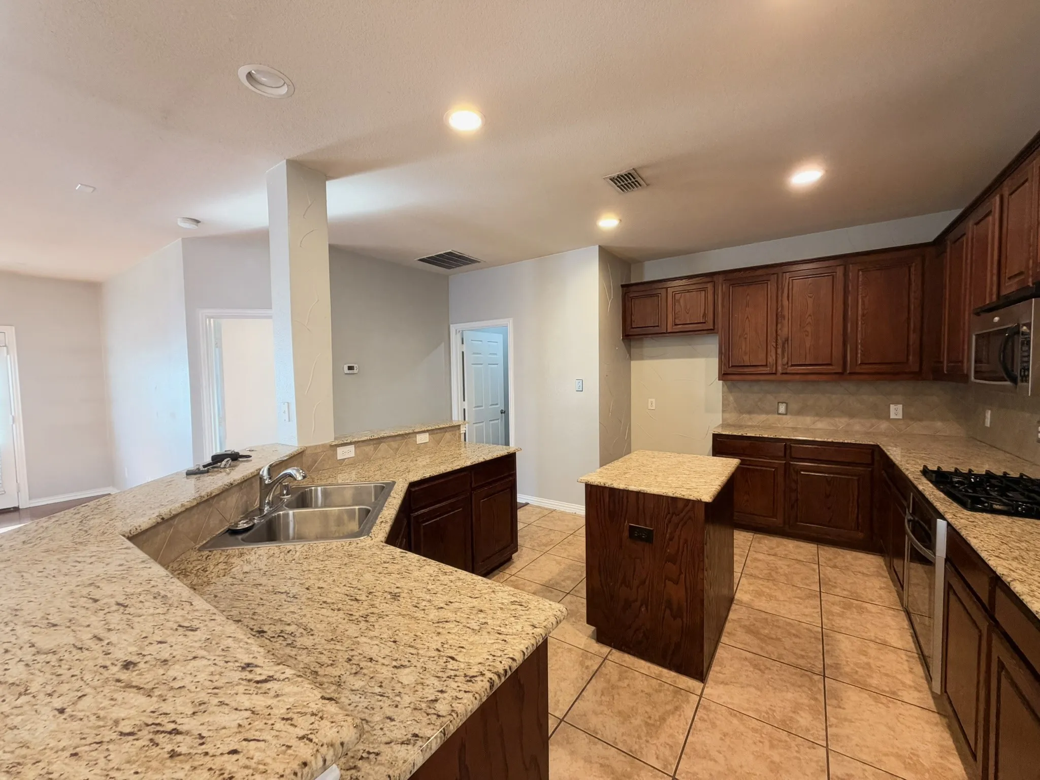 Kitchen featuring recessed lighting, a central island, wood cabinetry, granite countertops, and tile flooring