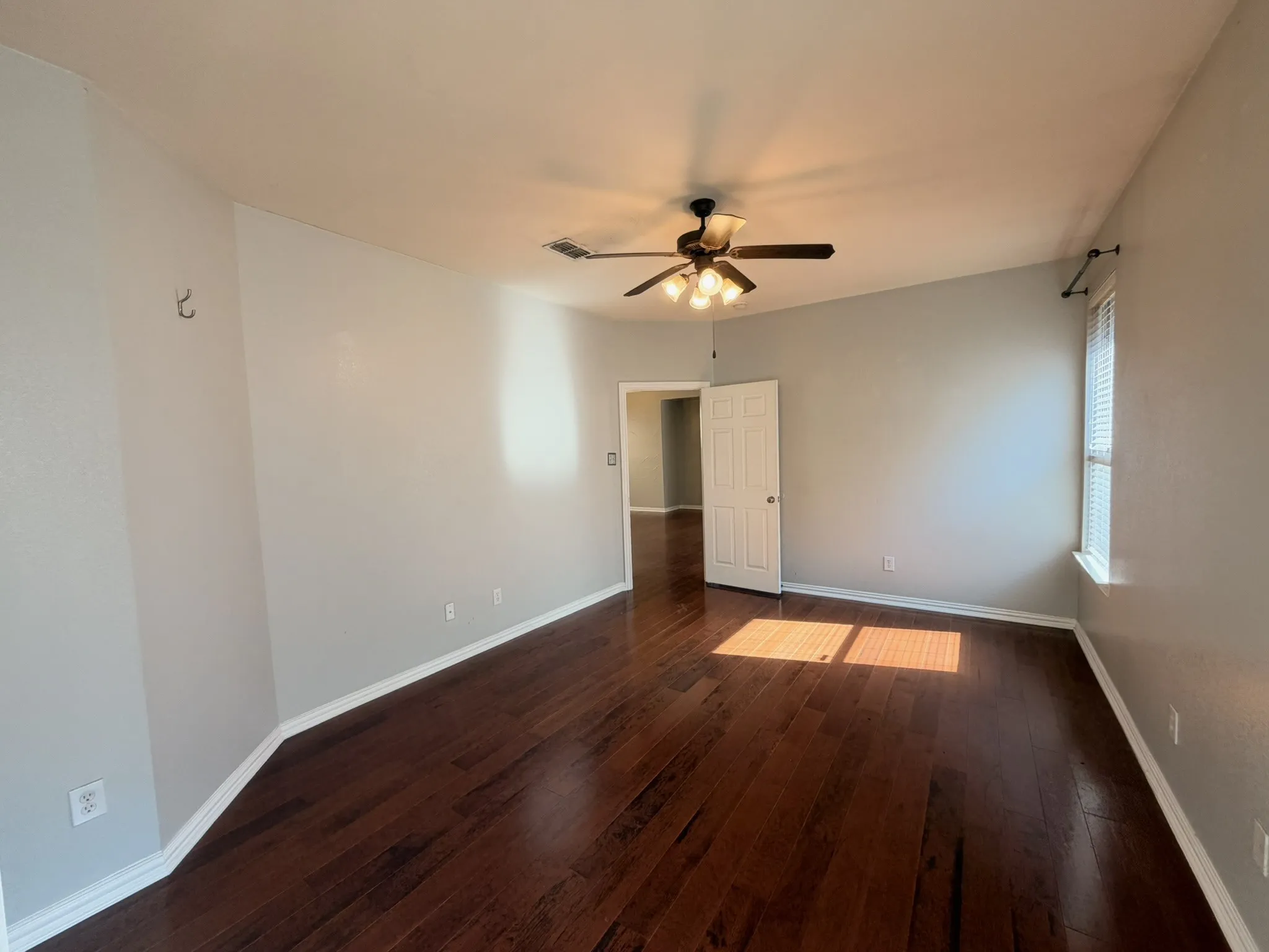Wood-finish flooring, ceiling fan with integrated lighting, neutral wall paint, and white trim
