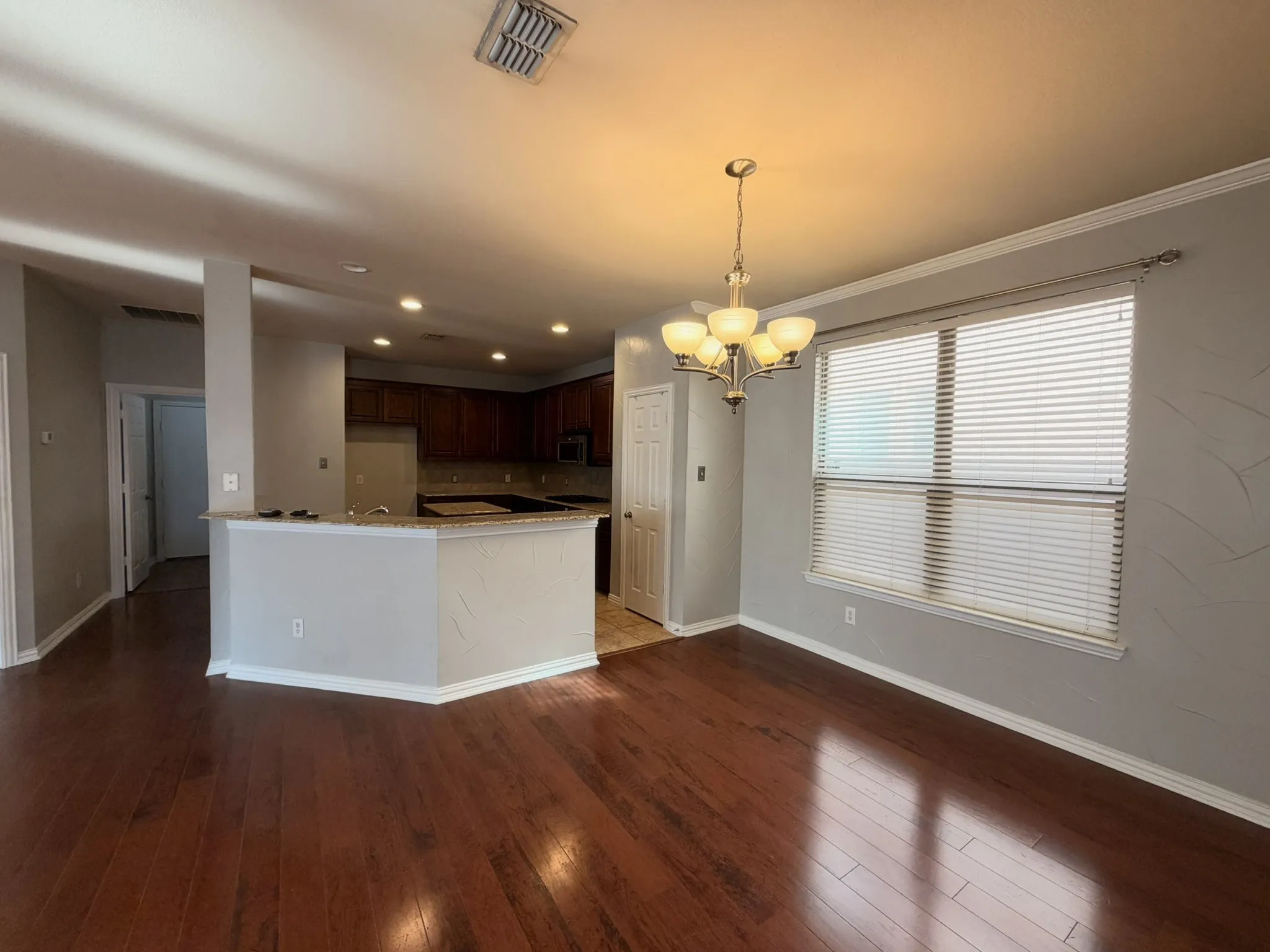 Open-concept living area featuring rich wood-finish flooring and a kitchen with dark cabinetry