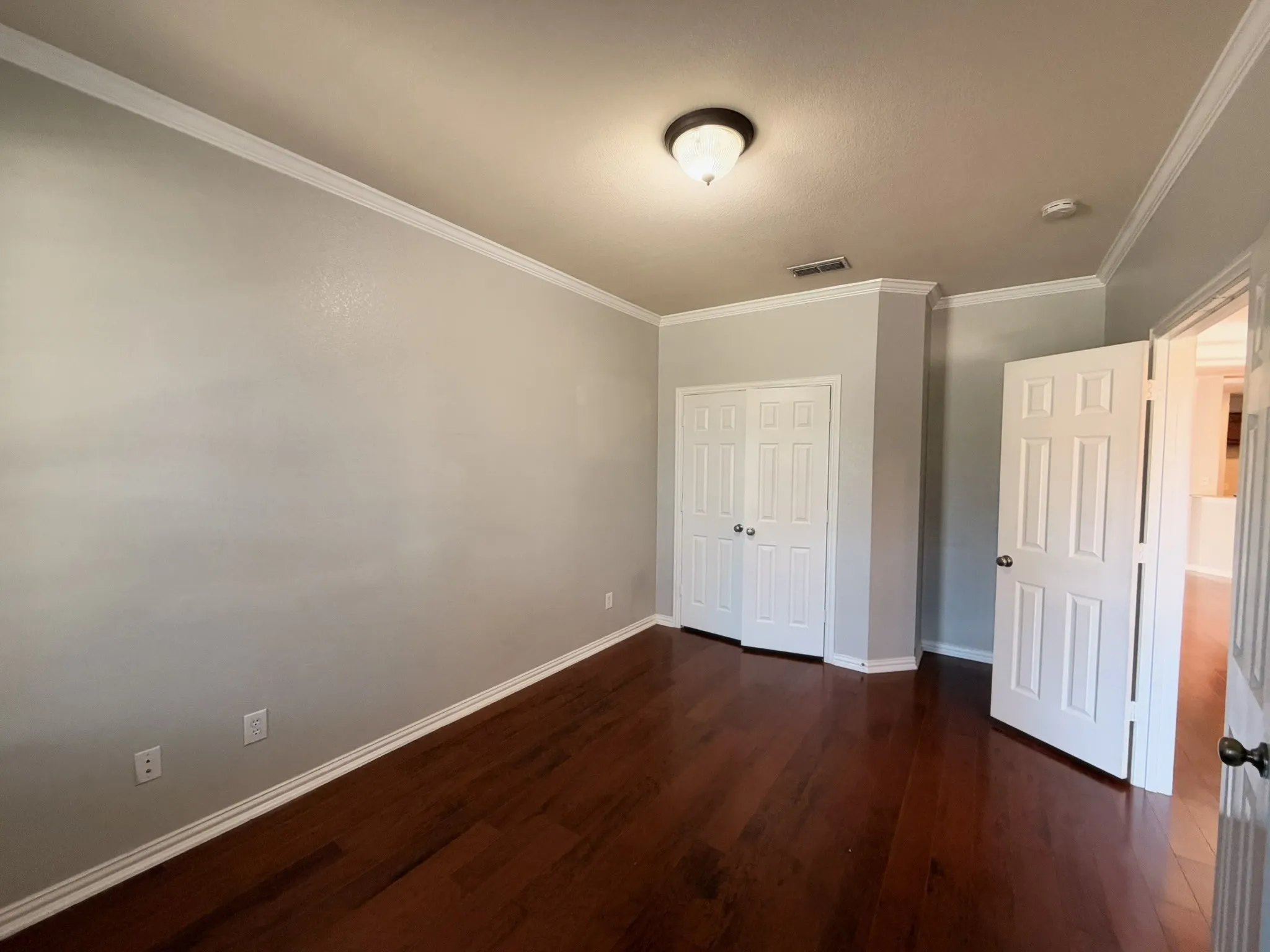 Wood-finish flooring, crown molding, and two panel doors