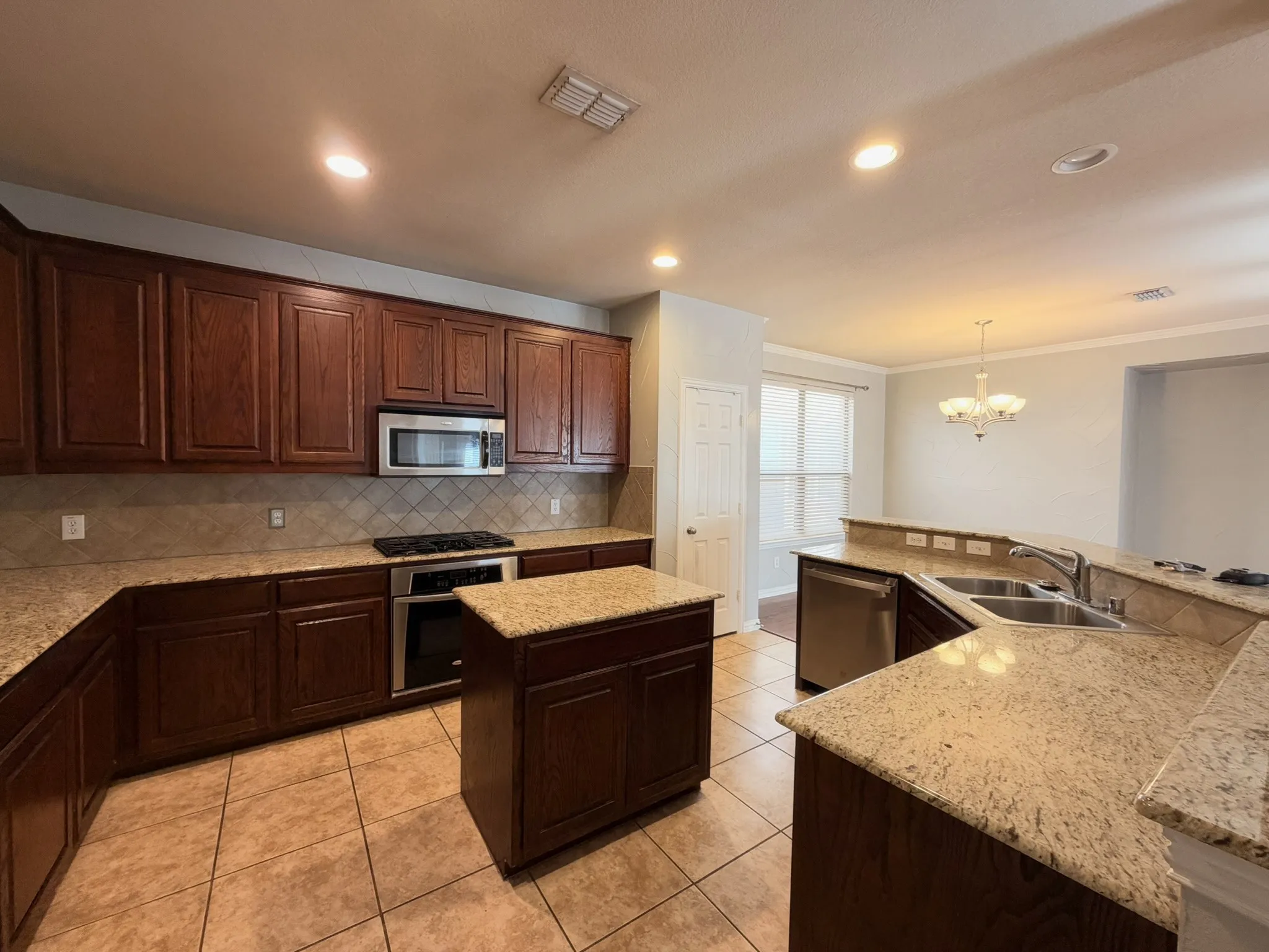 Kitchen featuring wood cabinetry, granite countertops, tile flooring, and stainless steel appliances