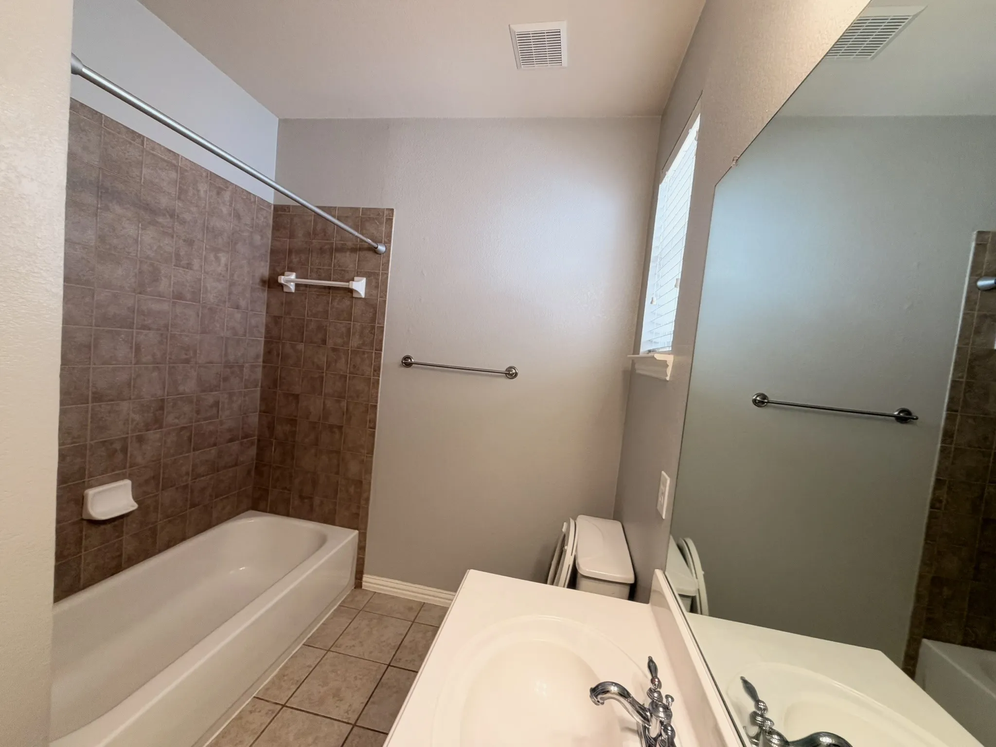 Bathroom featuring a white bathtub, full wall tile surround, vanity with an integrated sink, and a large wall-mounted mirror