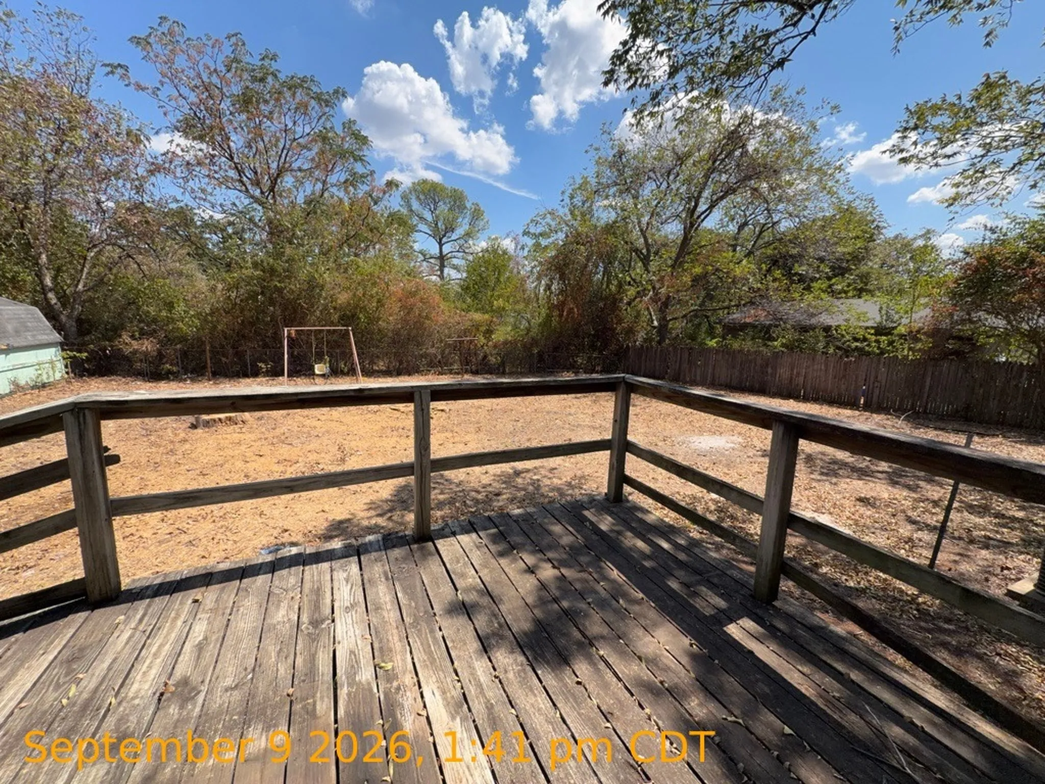 Expansive wood deck with a full railing, overlooking a substantial backyard area