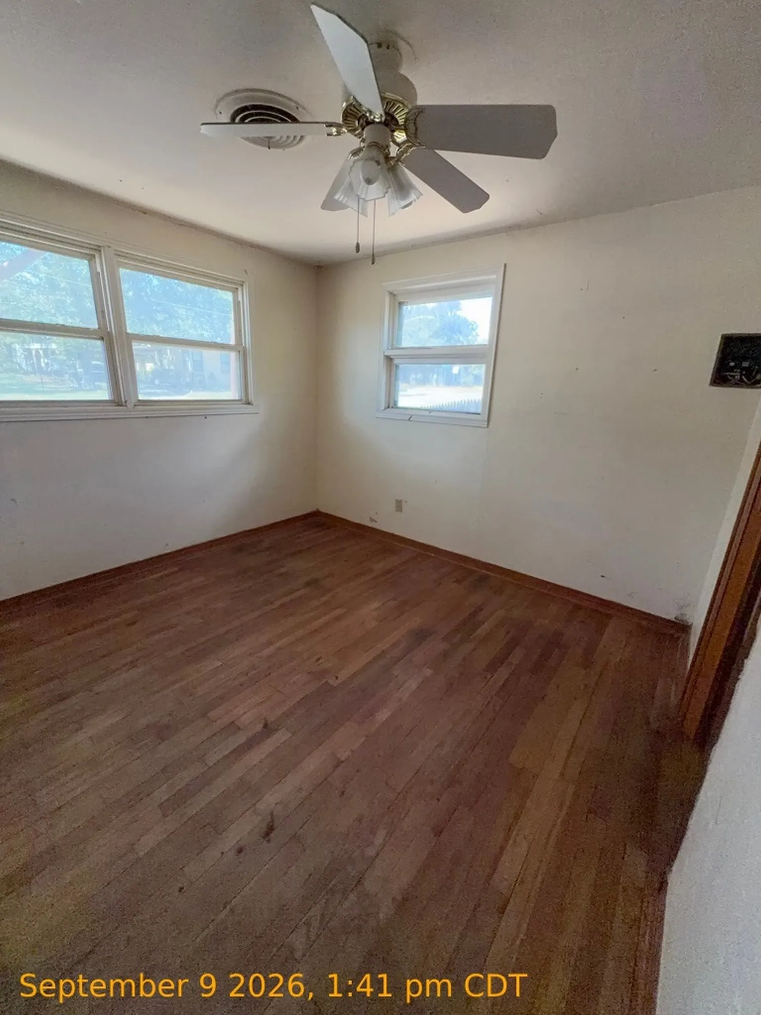 Hardwood flooring with multiple windows and a ceiling fan
