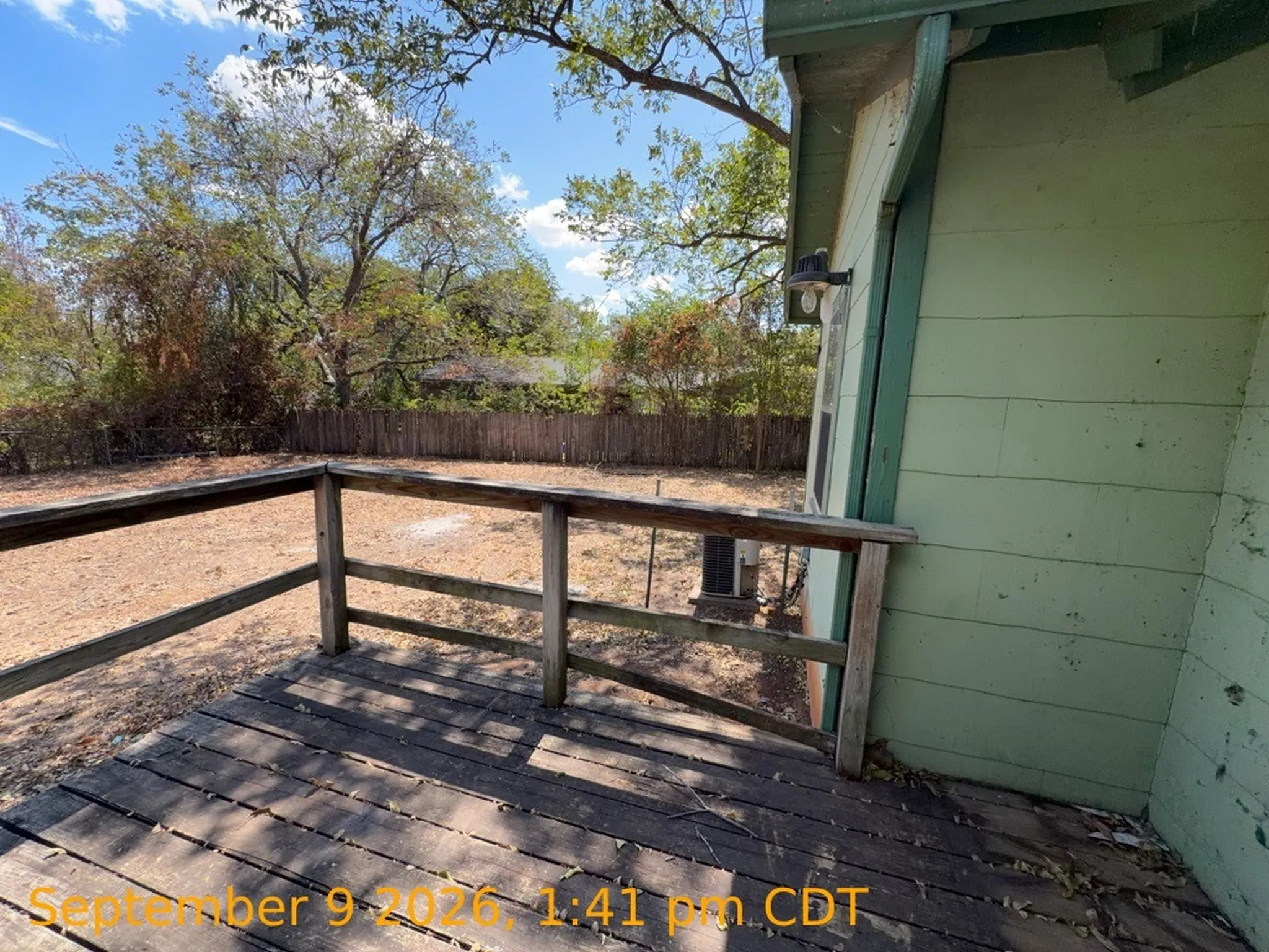 Wood deck with railing overlooking an expansive yard