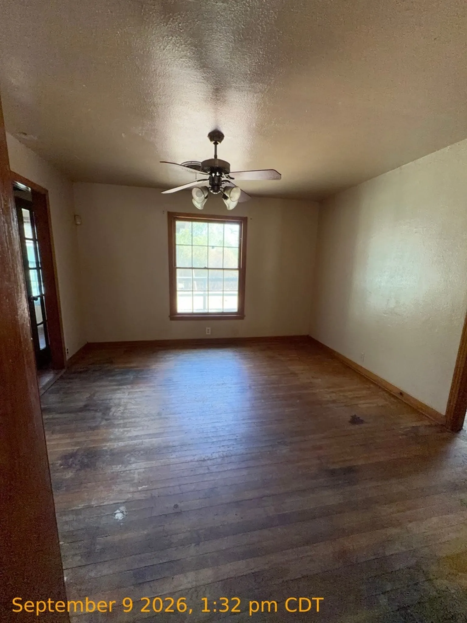 Hardwood flooring, ceiling fan with integrated lighting, and a window with wood trim