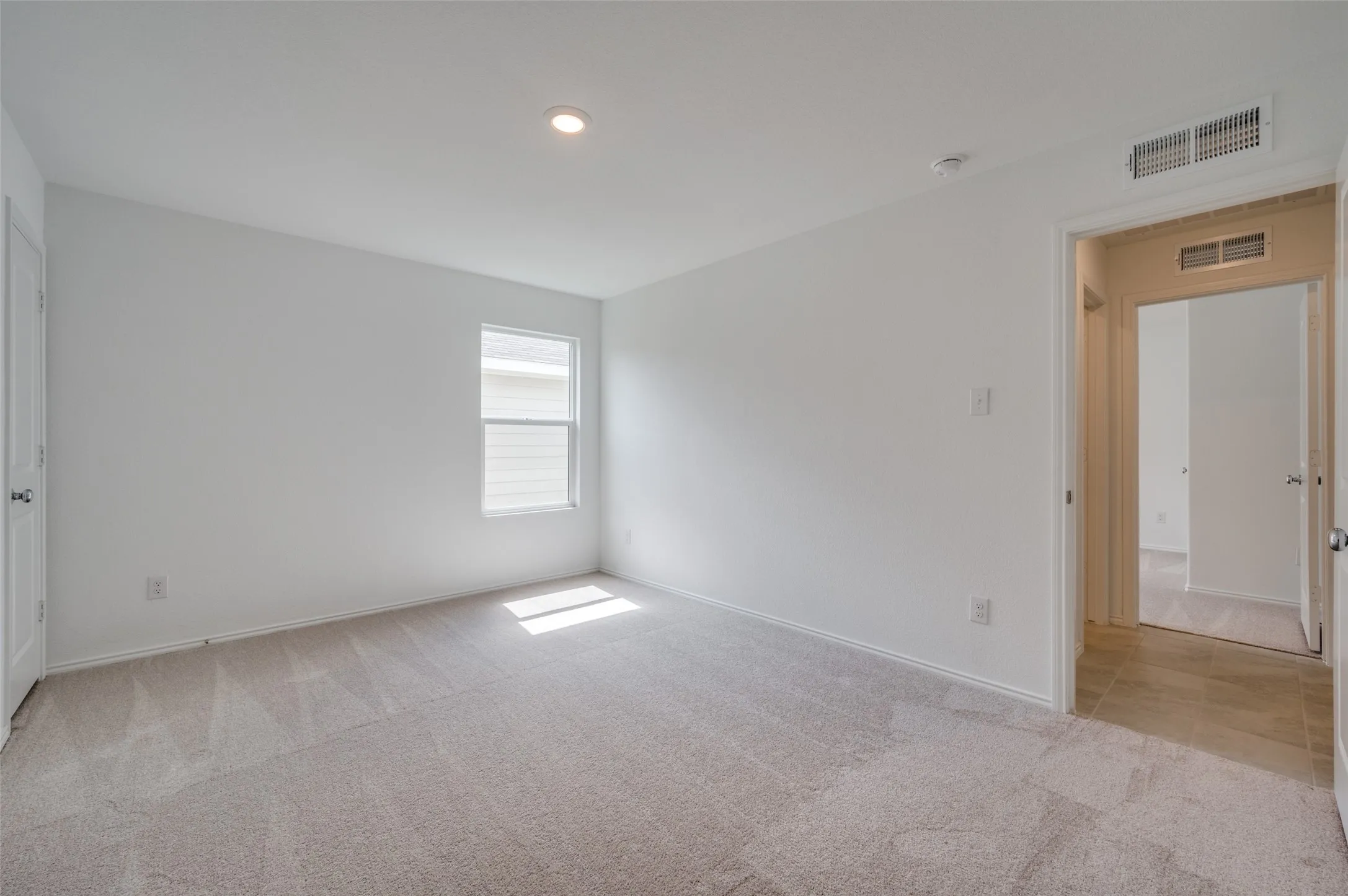 Empty room featuring light colored carpet