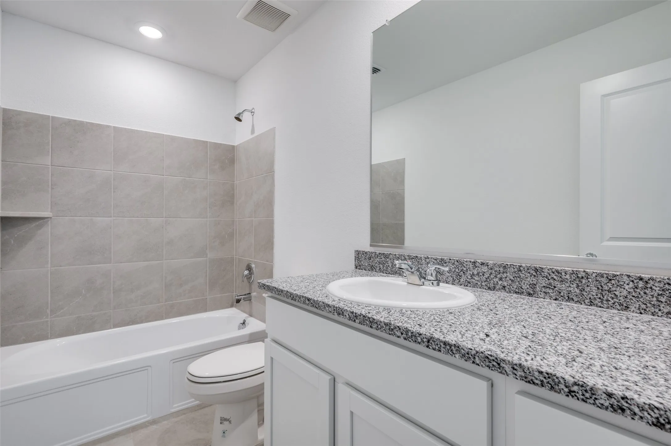 Full bathroom featuring tile flooring, oversized vanity, toilet, and tiled shower / bath combo