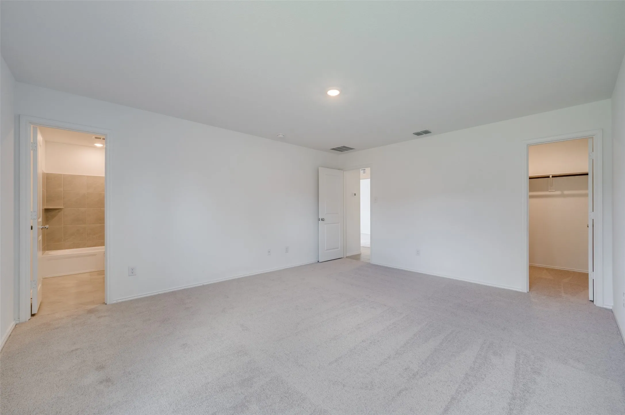 Unfurnished bedroom with a closet, carpet floors, connected bathroom, and a walk in closet