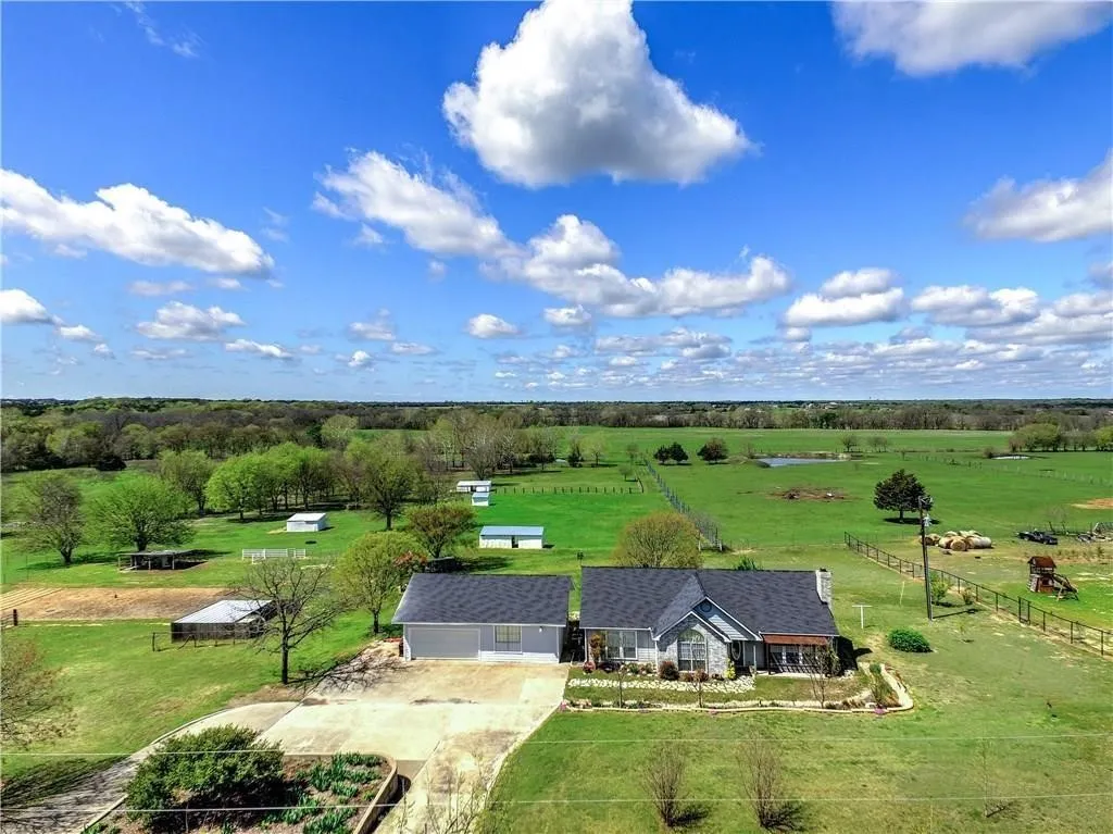 Ranch-style residence with an attached garage, paved driveway, and extensive surrounding green space