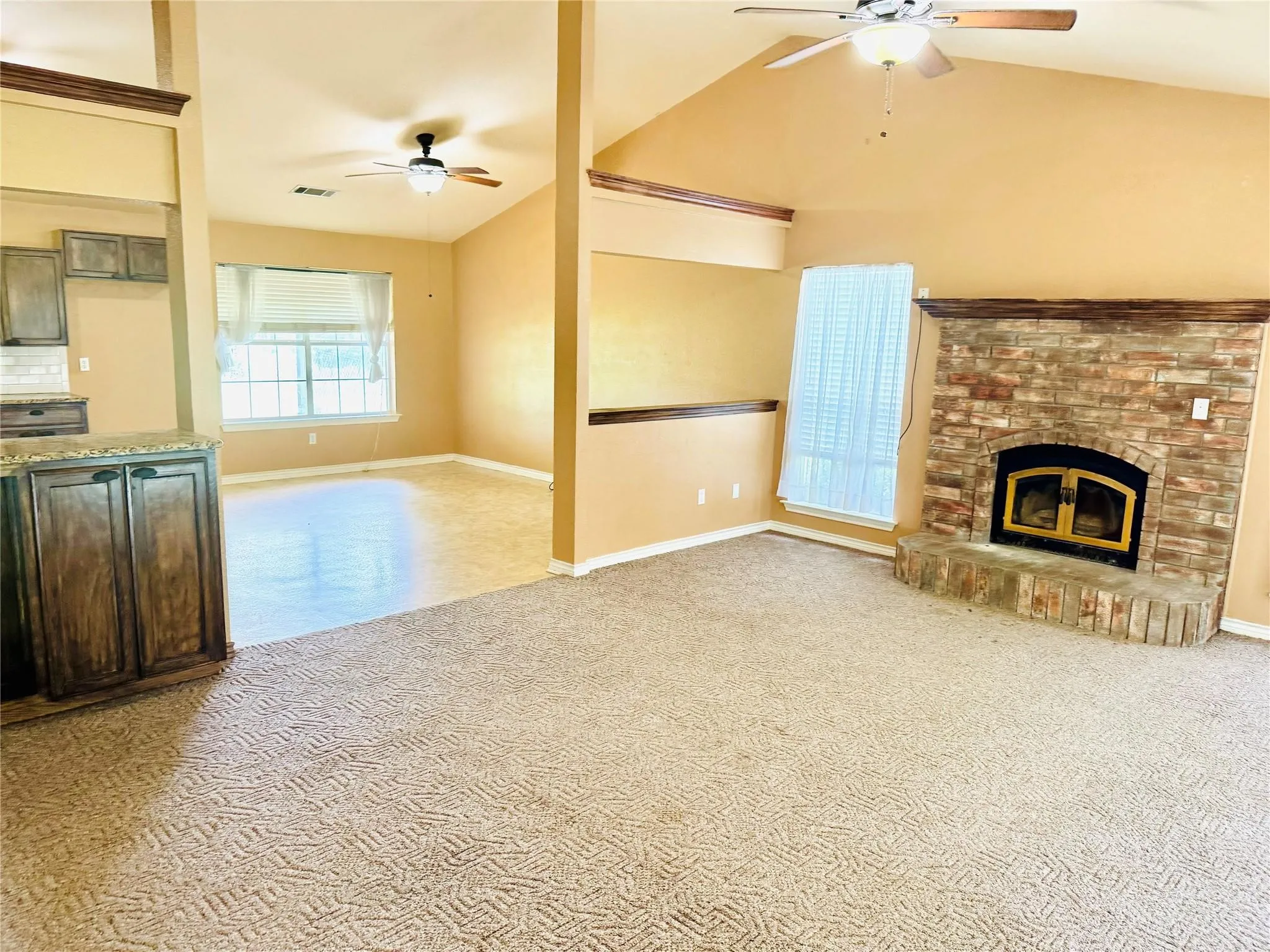 Living area featuring a stone-clad fireplace with hearth, vaulted ceiling, and ceiling fan