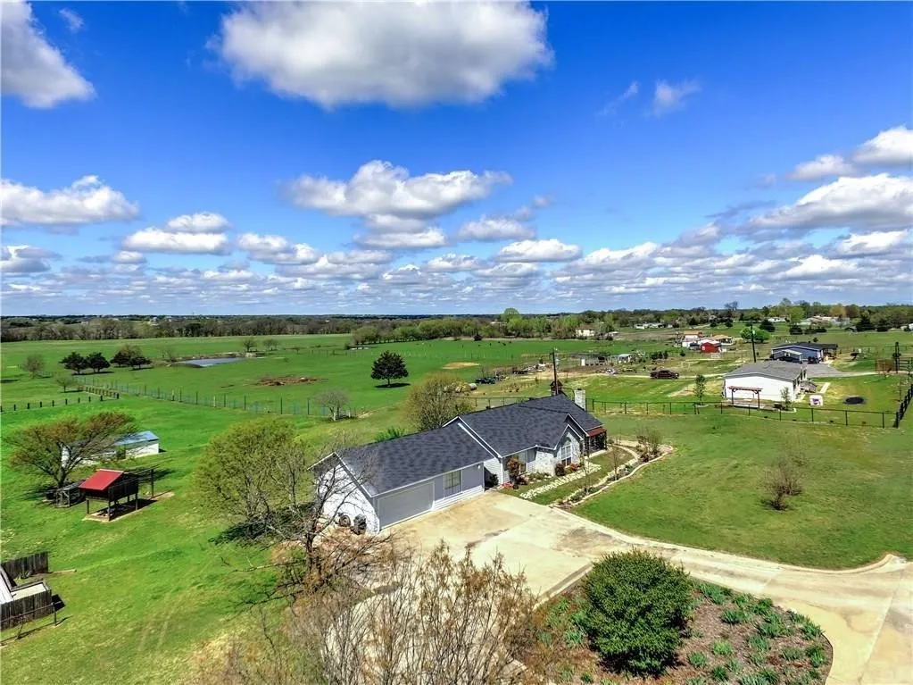 Spacious property with a large, gabled roofline, attached garage, concrete driveway, and expansive green lawns