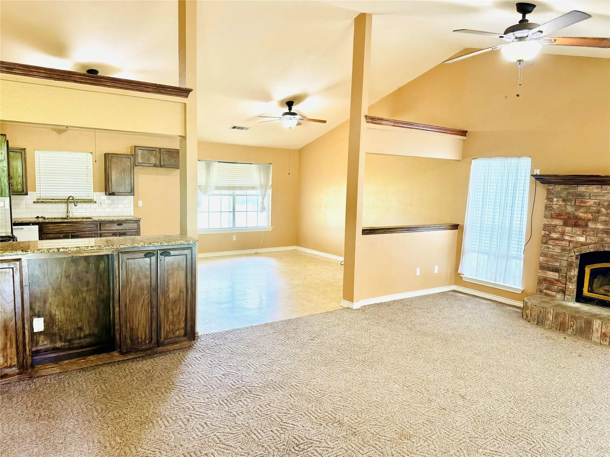 Kitchen with wood-finish cabinetry, granite-style countertops, and a tile backsplash