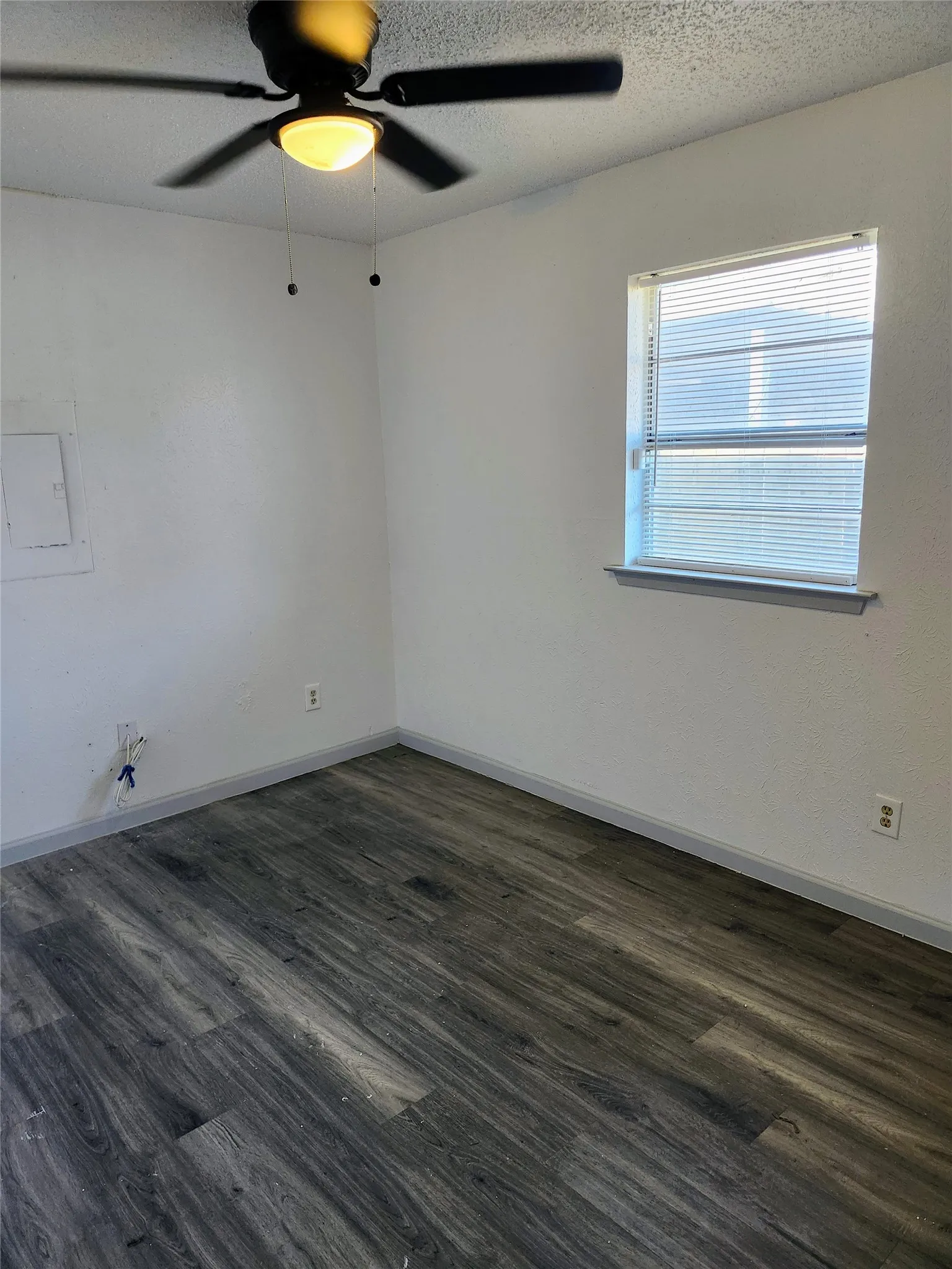 Primary Bedroom - Wood-finish flooring, ceiling fan with integrated lighting, and a window with blinds