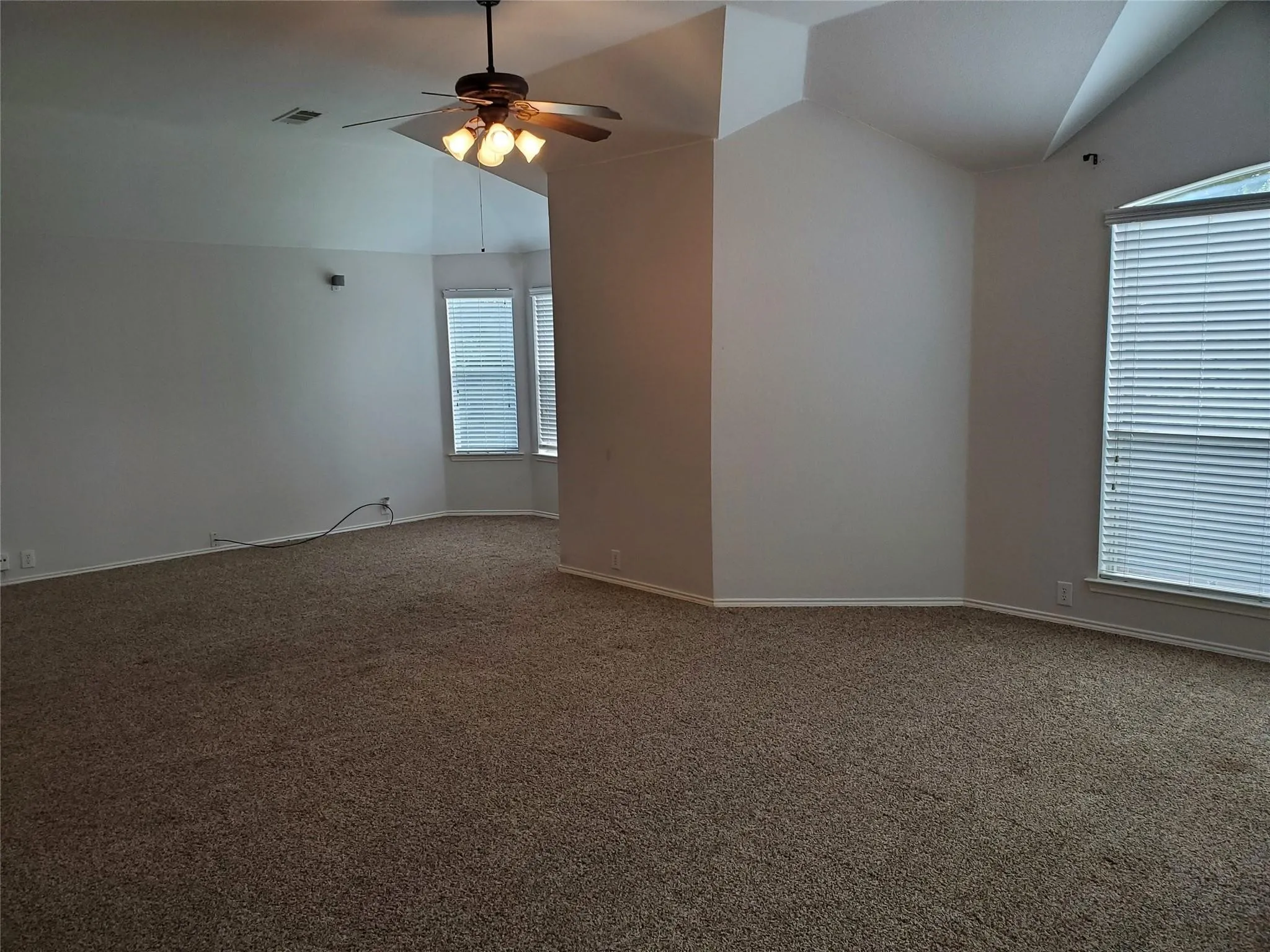 Unfurnished room featuring ceiling fan, vaulted ceiling, and carpet floors