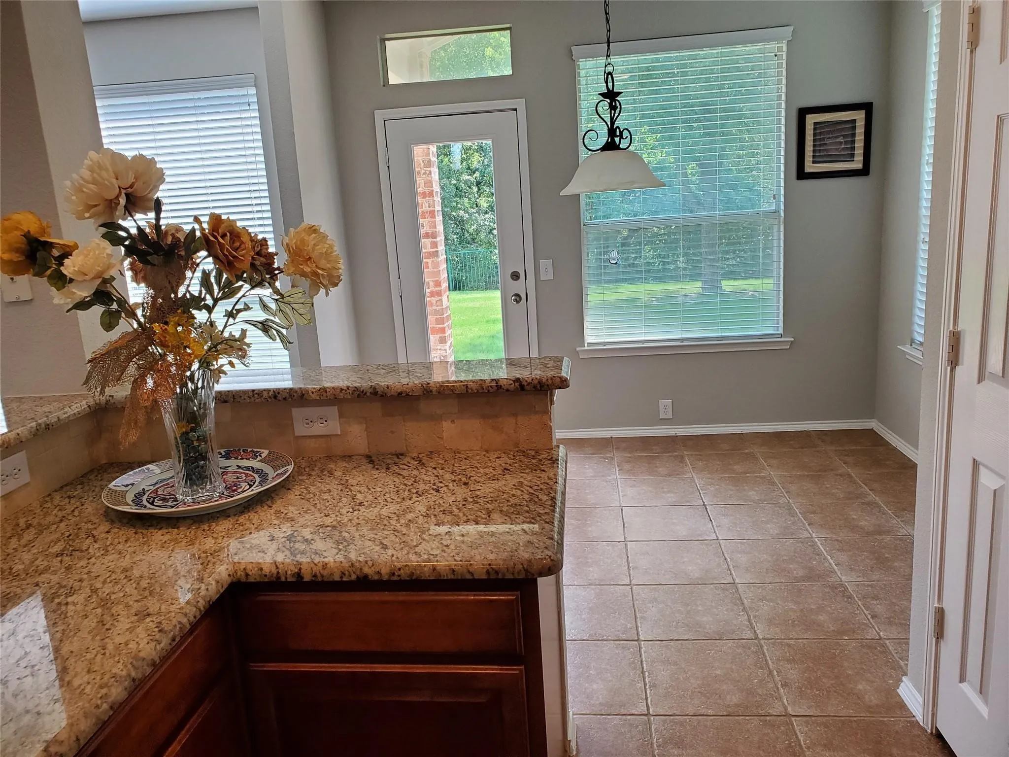 Kitchen featuring light tile patterned floors, hanging light fixtures, and light stone countertops
