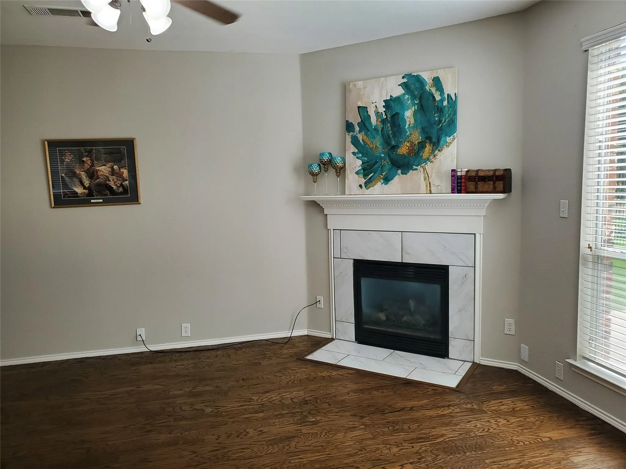 Unfurnished living room featuring ceiling fan, a fireplace, wood-type flooring, and a wealth of natural light