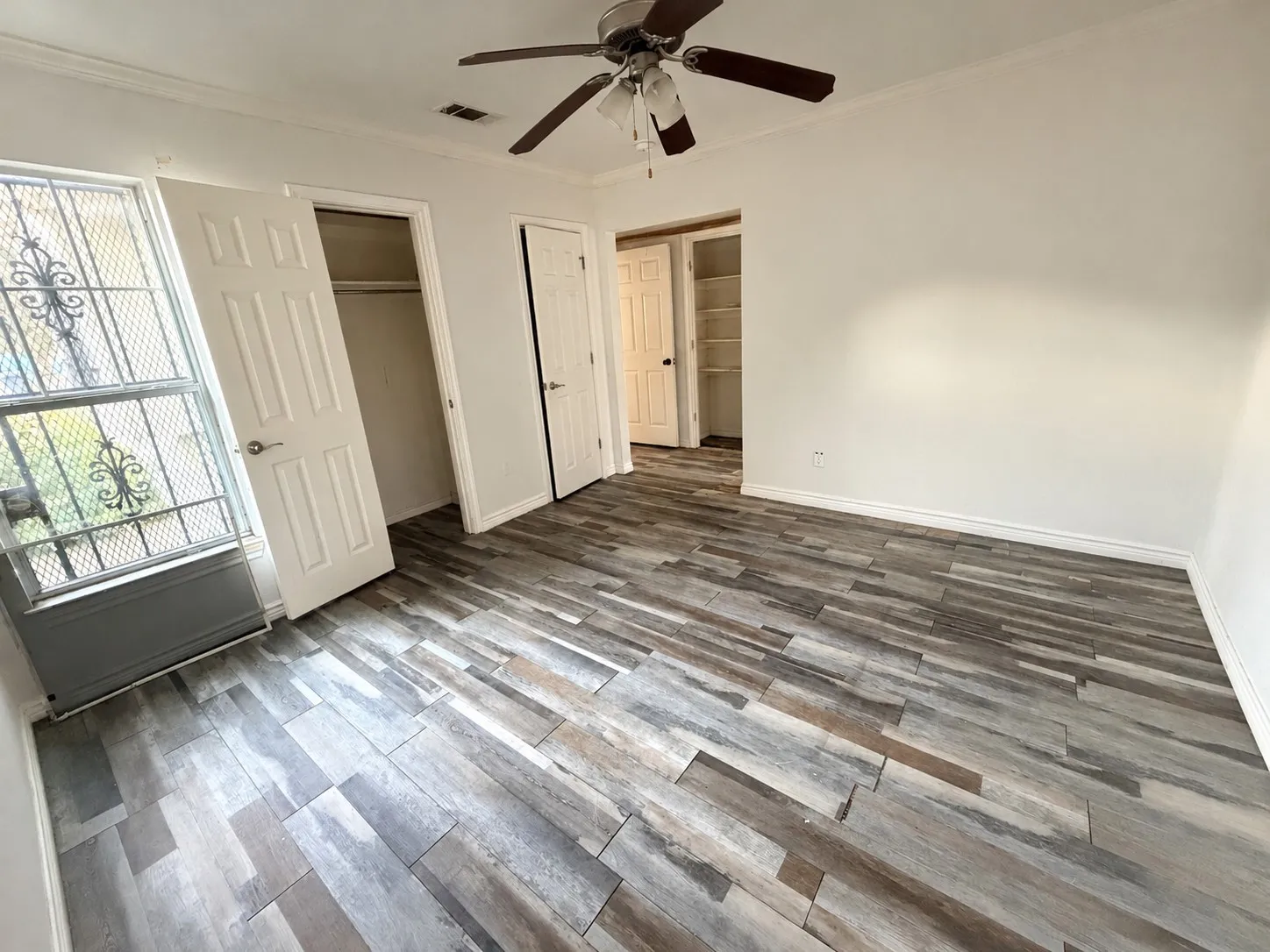 Wood-look plank flooring, ceiling fan, white trim, and multiple doorways
