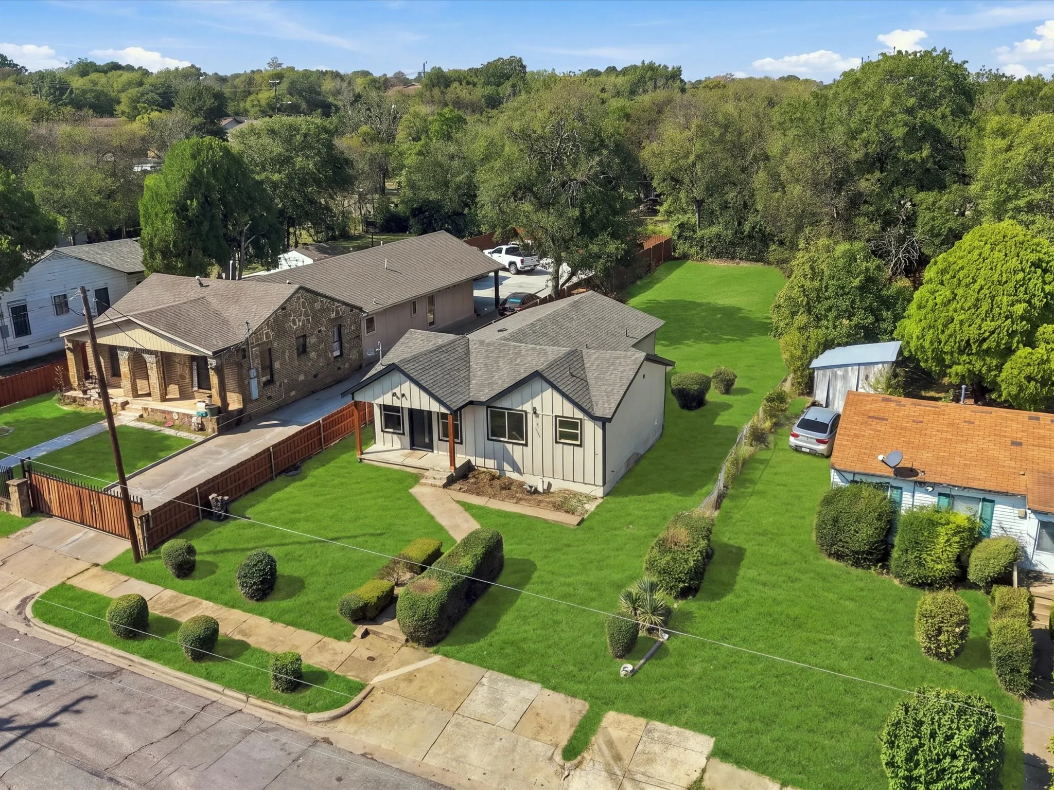 Wood-sided exterior with a gabled roof, front yard with mature landscaping, and a long driveway