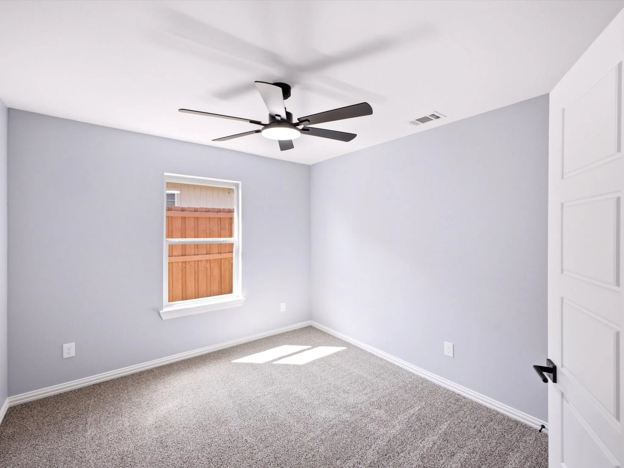 Gray wall paint, white trim, grey carpet, ceiling fan, and white panel door