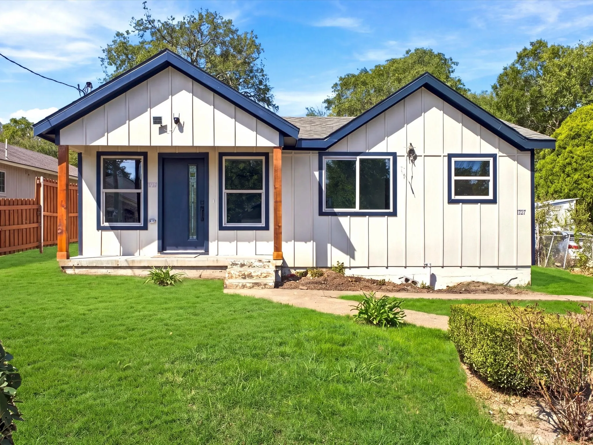 Board-and-batten siding with a contrasting dark trim, covered porch entry, and a dark-paneled front door
