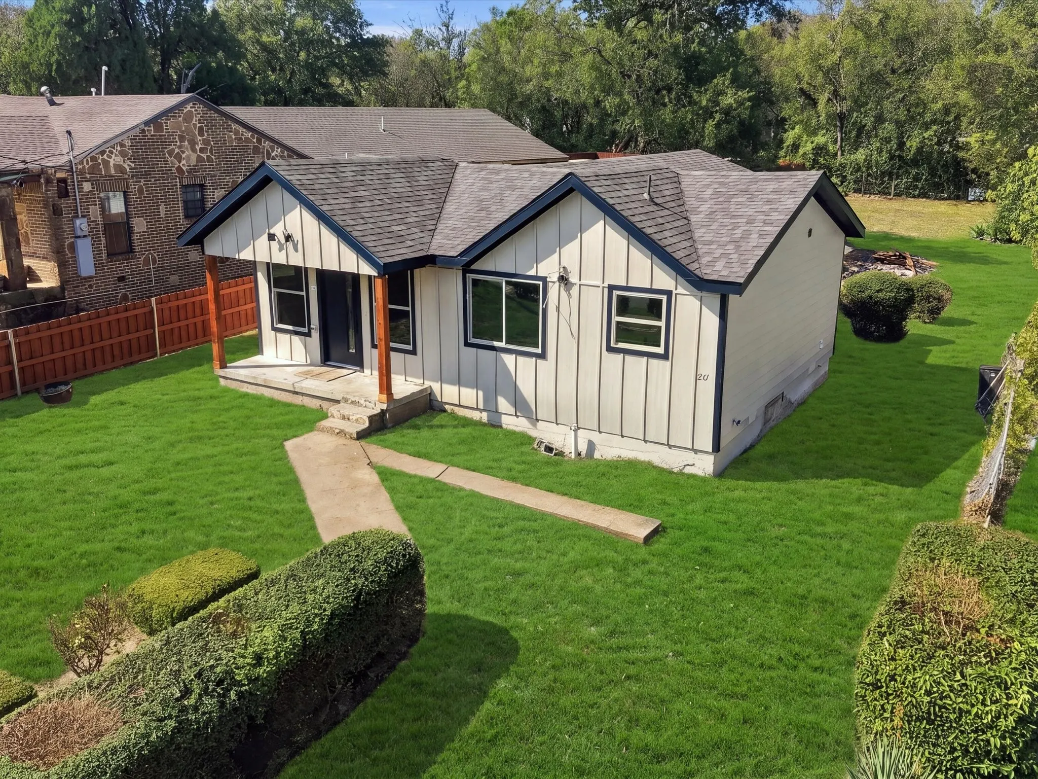 Exterior featuring vertical siding with dark trim accents, a dark shingle roof, a covered porch with wood posts, and a concrete walkway