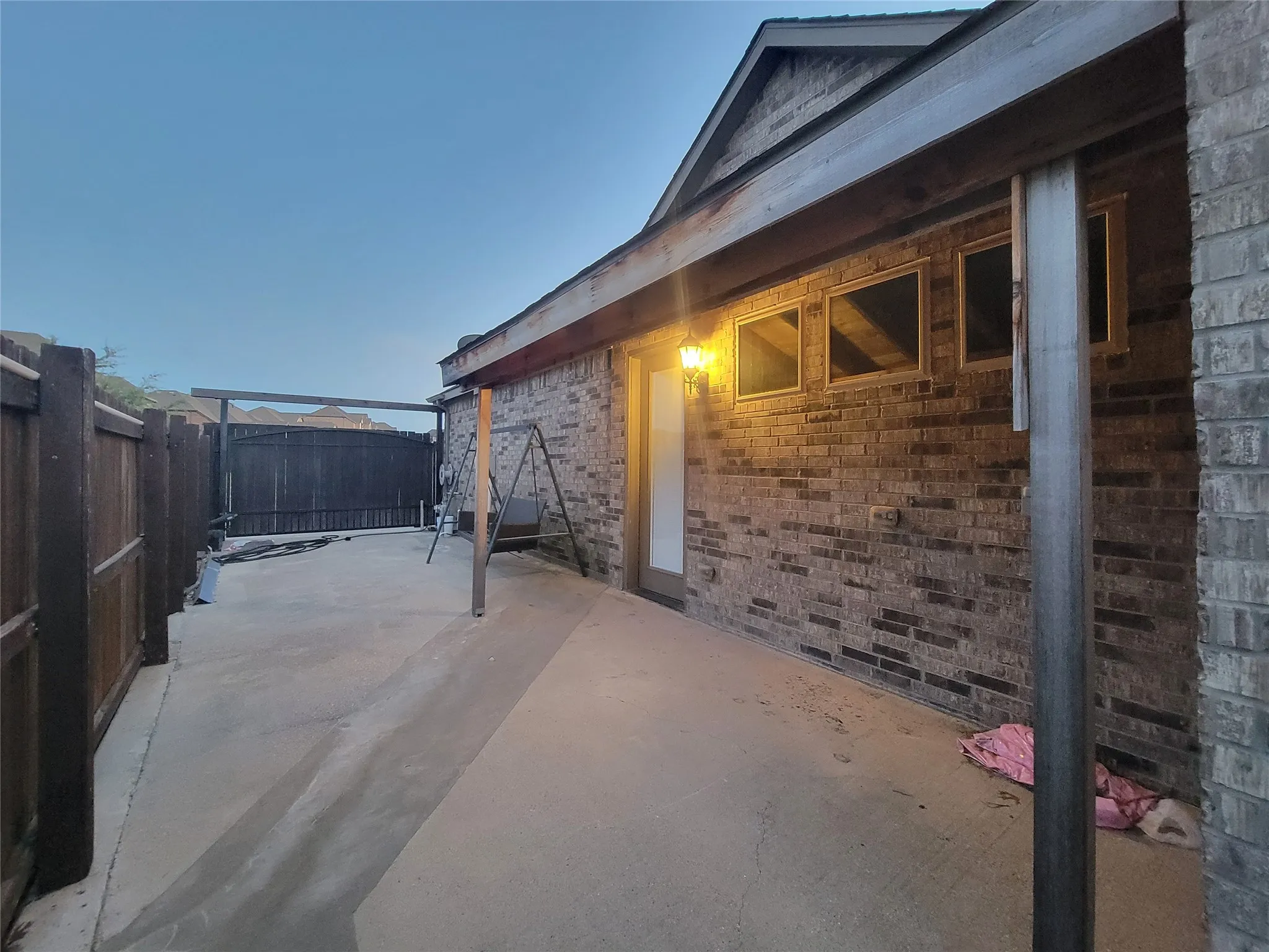 Paved patio area, brick exterior, exterior lighting fixture, privacy fencing, multiple exterior windows