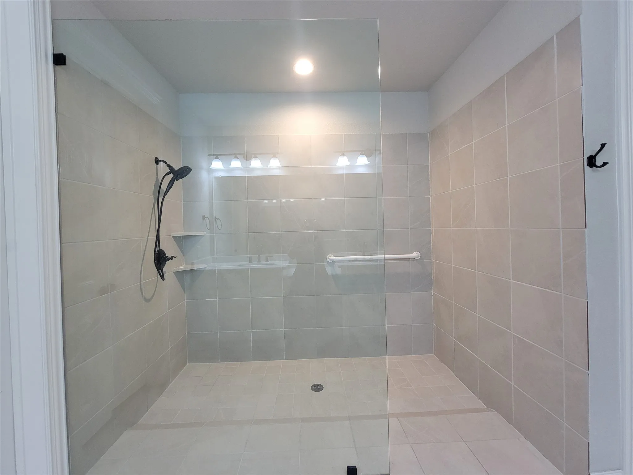 Walk-in shower with full tile surround, glass enclosure, and matte black shower fixtures