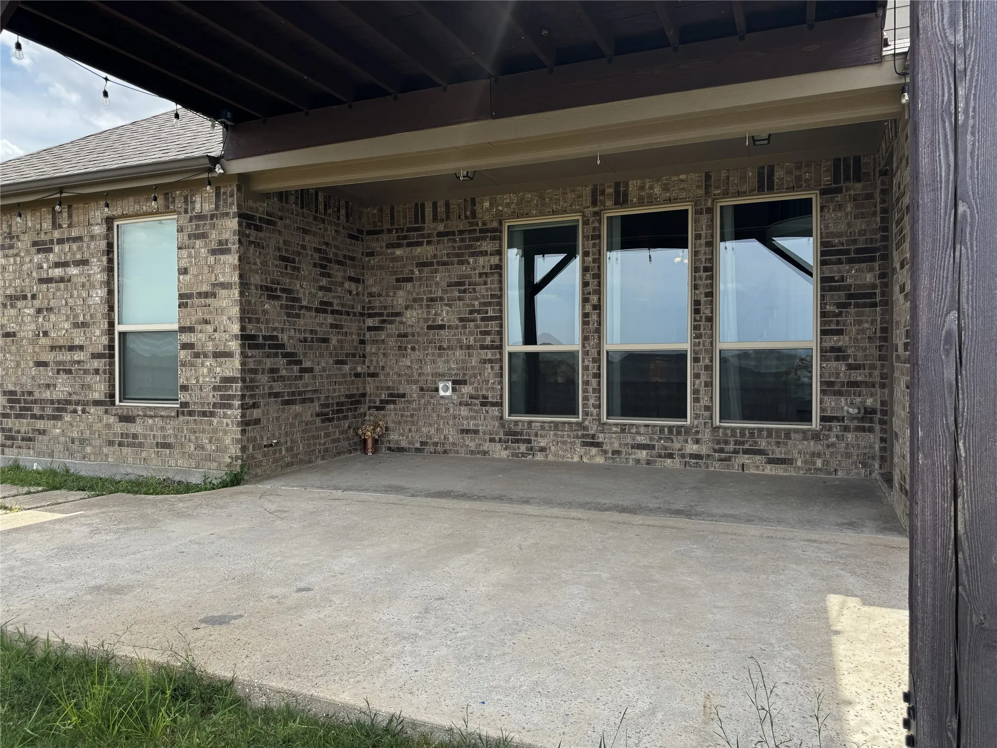 Covered patio with a concrete surface, brick exterior, and multiple large windows