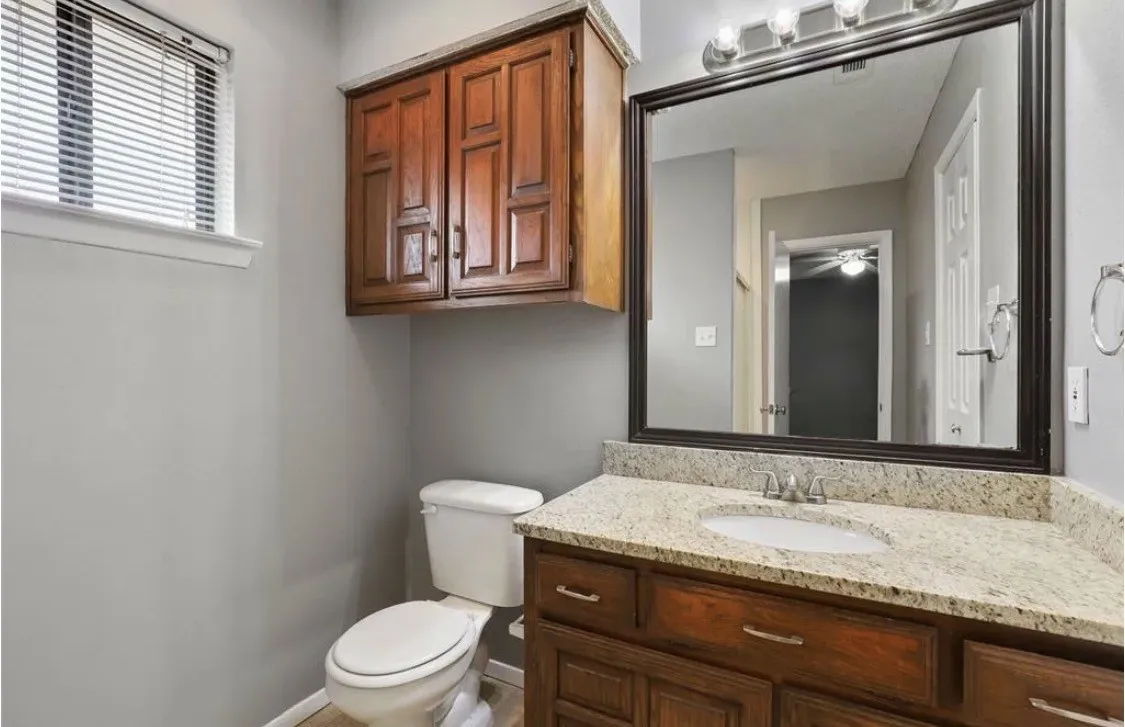Vanity with granite-style countertop, integrated sink, and wood-finish cabinetry
