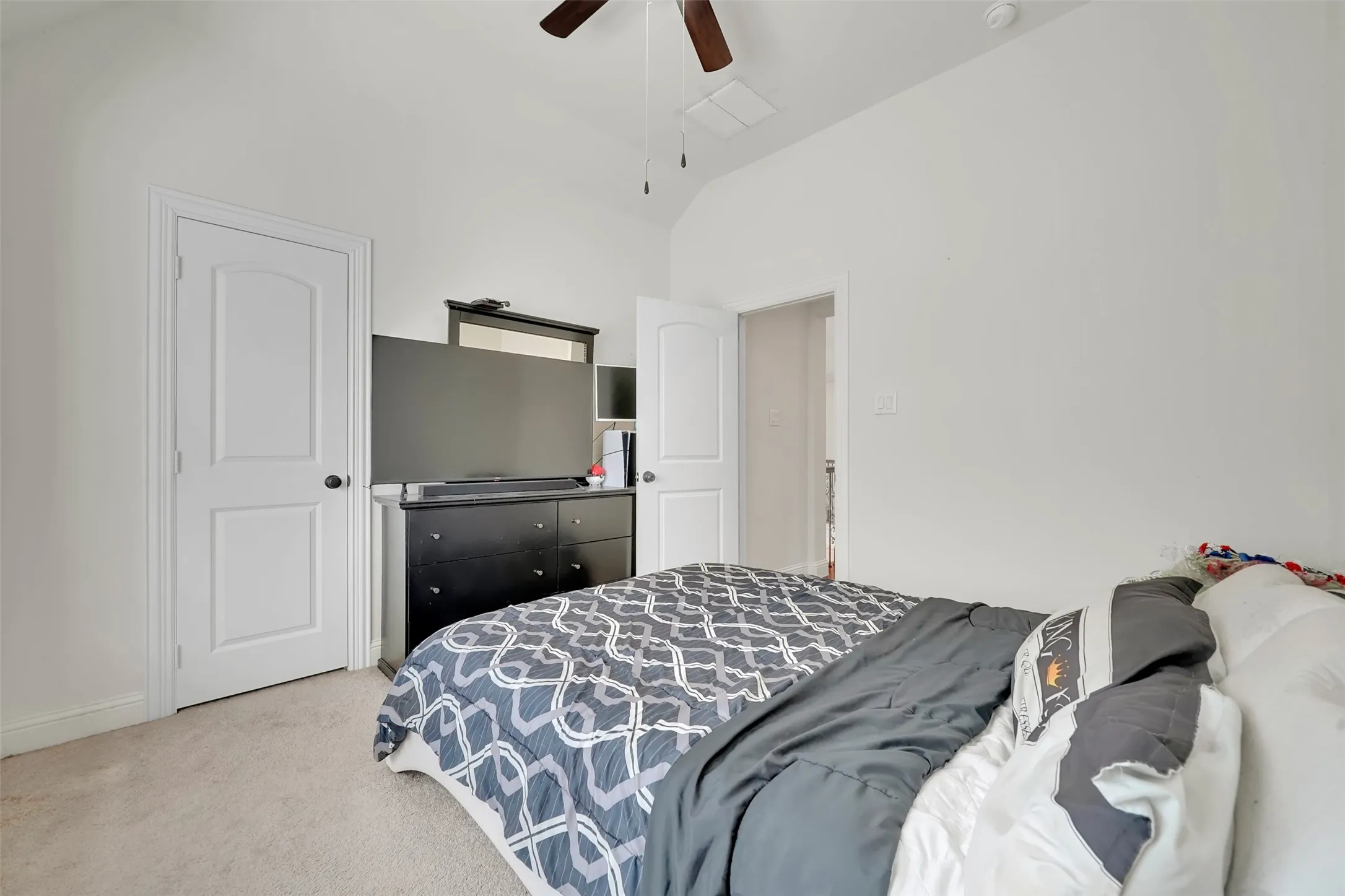 Vaulted ceiling with a ceiling fan, white paneled doors, and light-toned carpet flooring