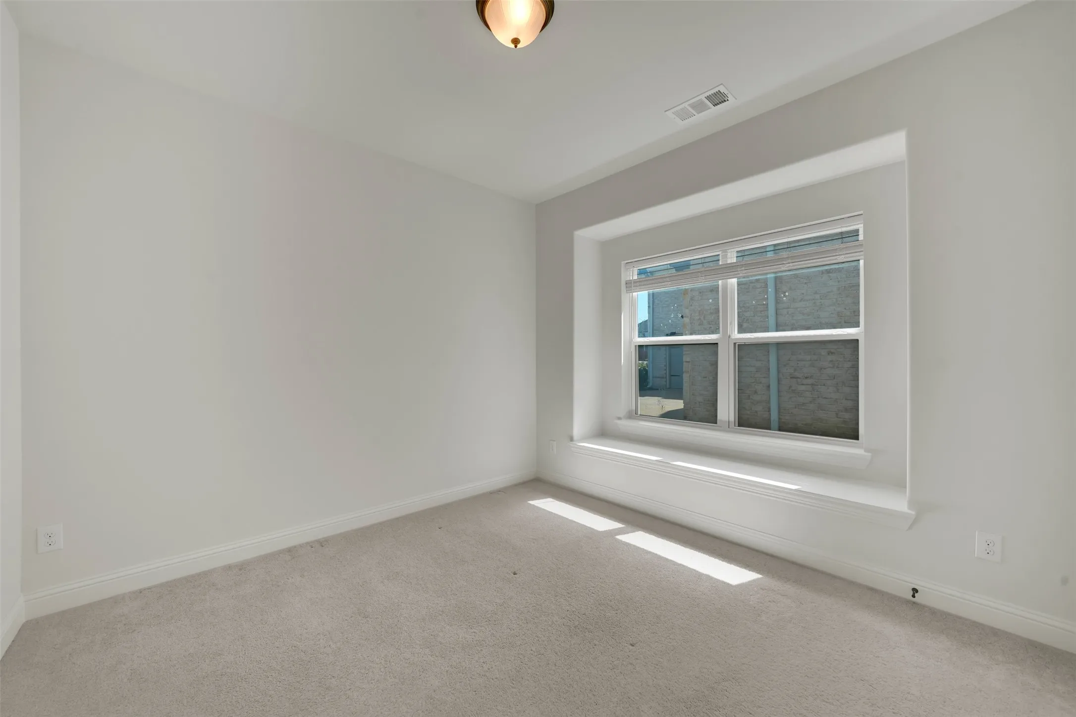 Neutral paint palette with light gray carpeting, recessed window featuring a broad sill, and a flush-mount ceiling light