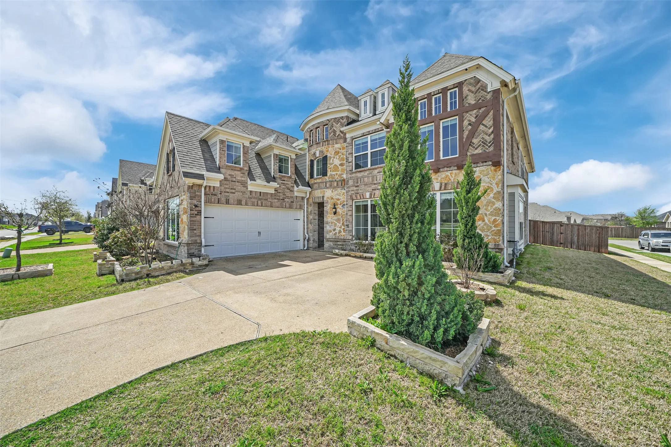 Stone and siding exterior with decorative wood accents, multi-pane windows, dormer windows, and an attached two-car garage