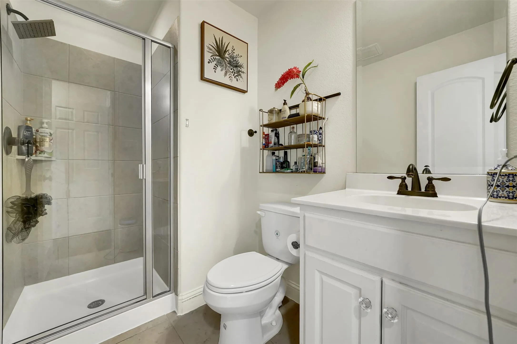 Shower enclosure with clear glass door, tile surround, and square shower head
