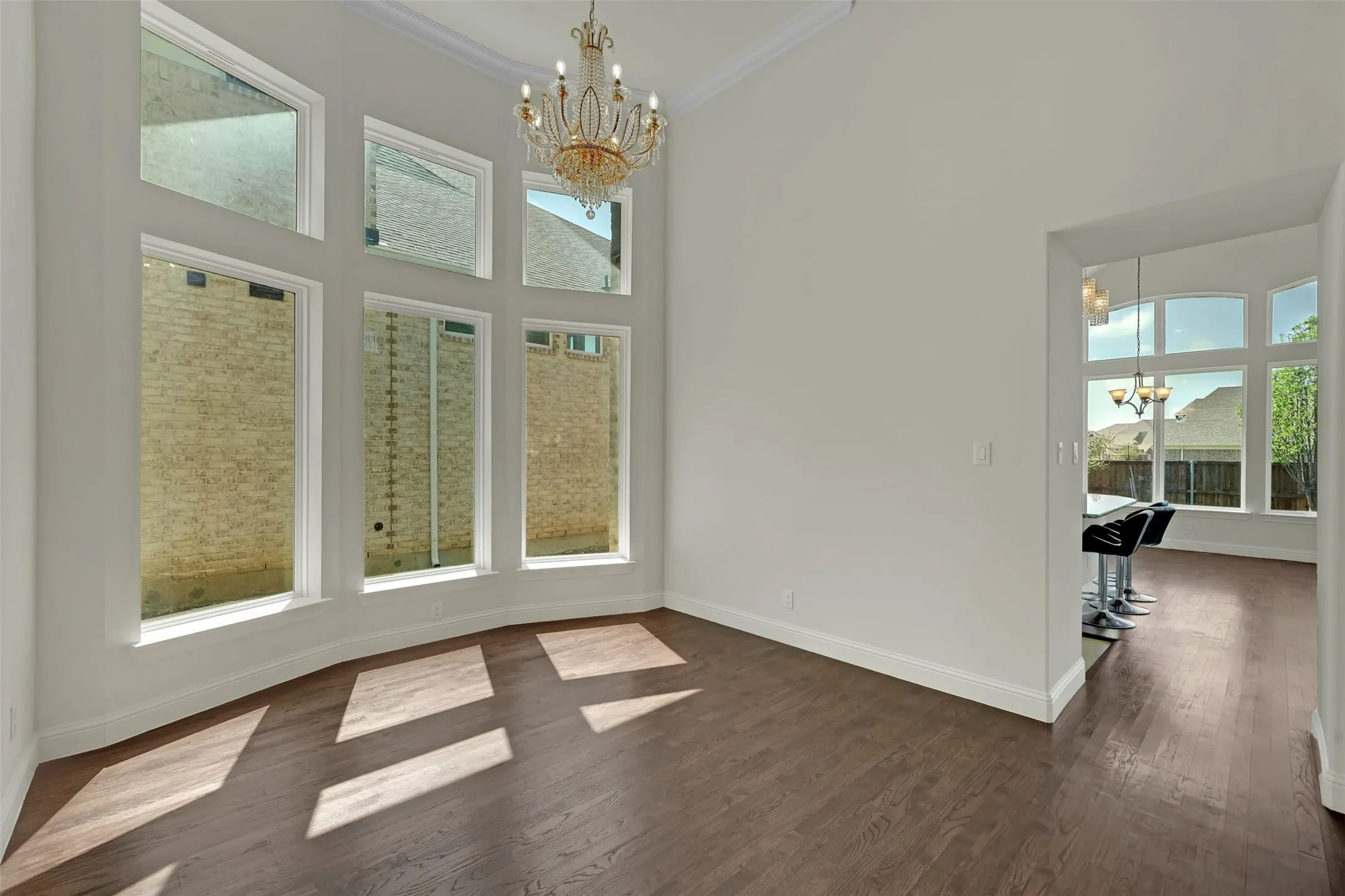 High ceilings with crown molding, wood-finish flooring, and a multi-tiered crystal chandelier