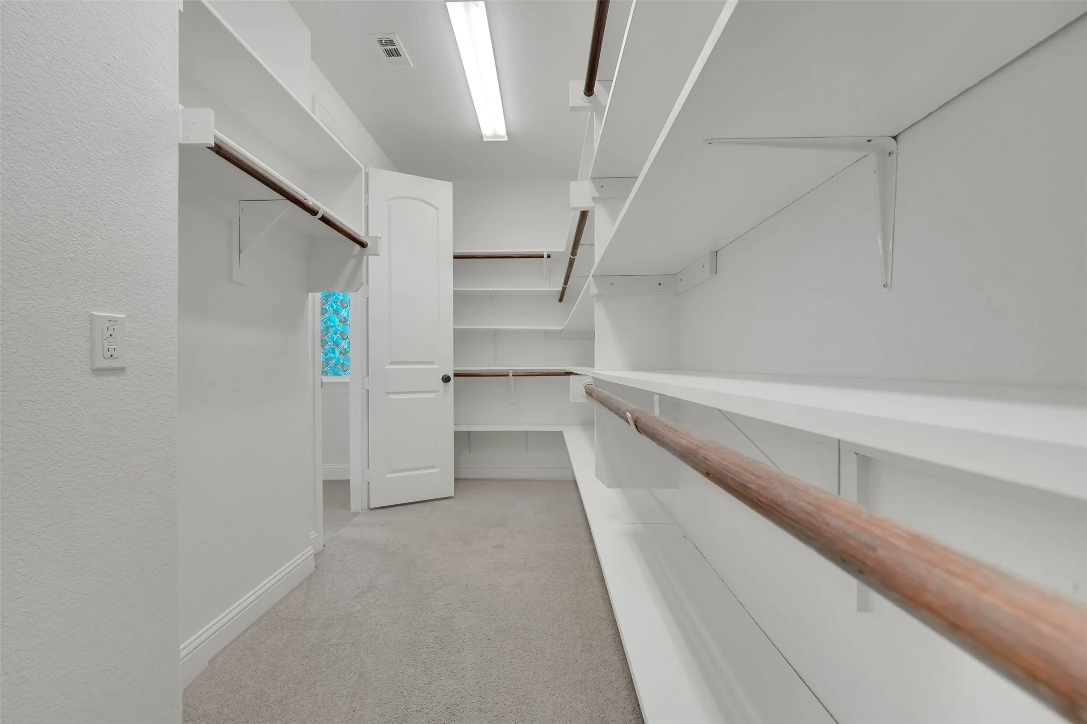 Walk-in closet featuring extensive built-in shelving, multiple hanging rods, and recessed lighting