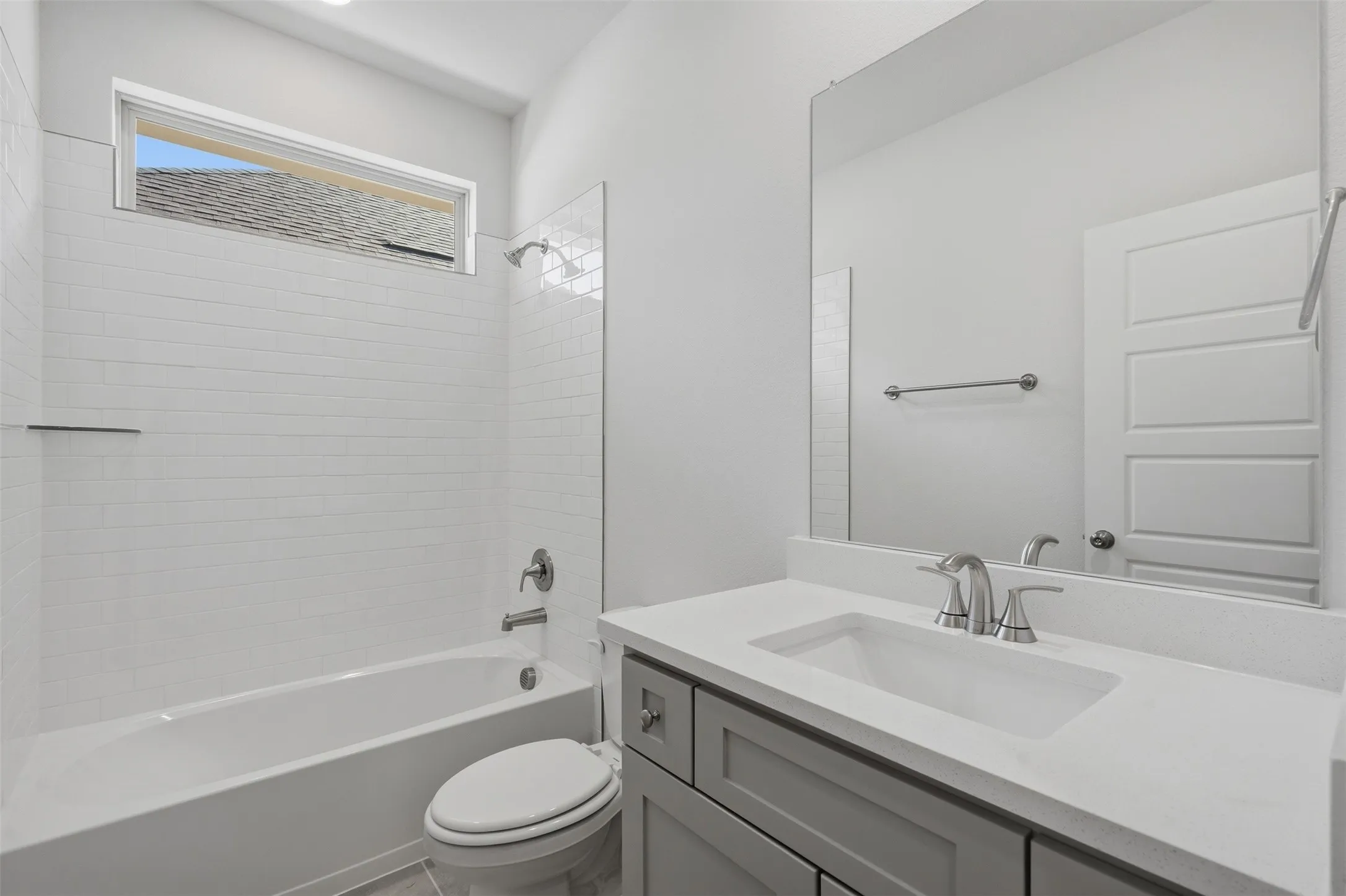Bathtub with subway tile surround, sleek vanity with an integrated sink, and a large wall-mounted mirror