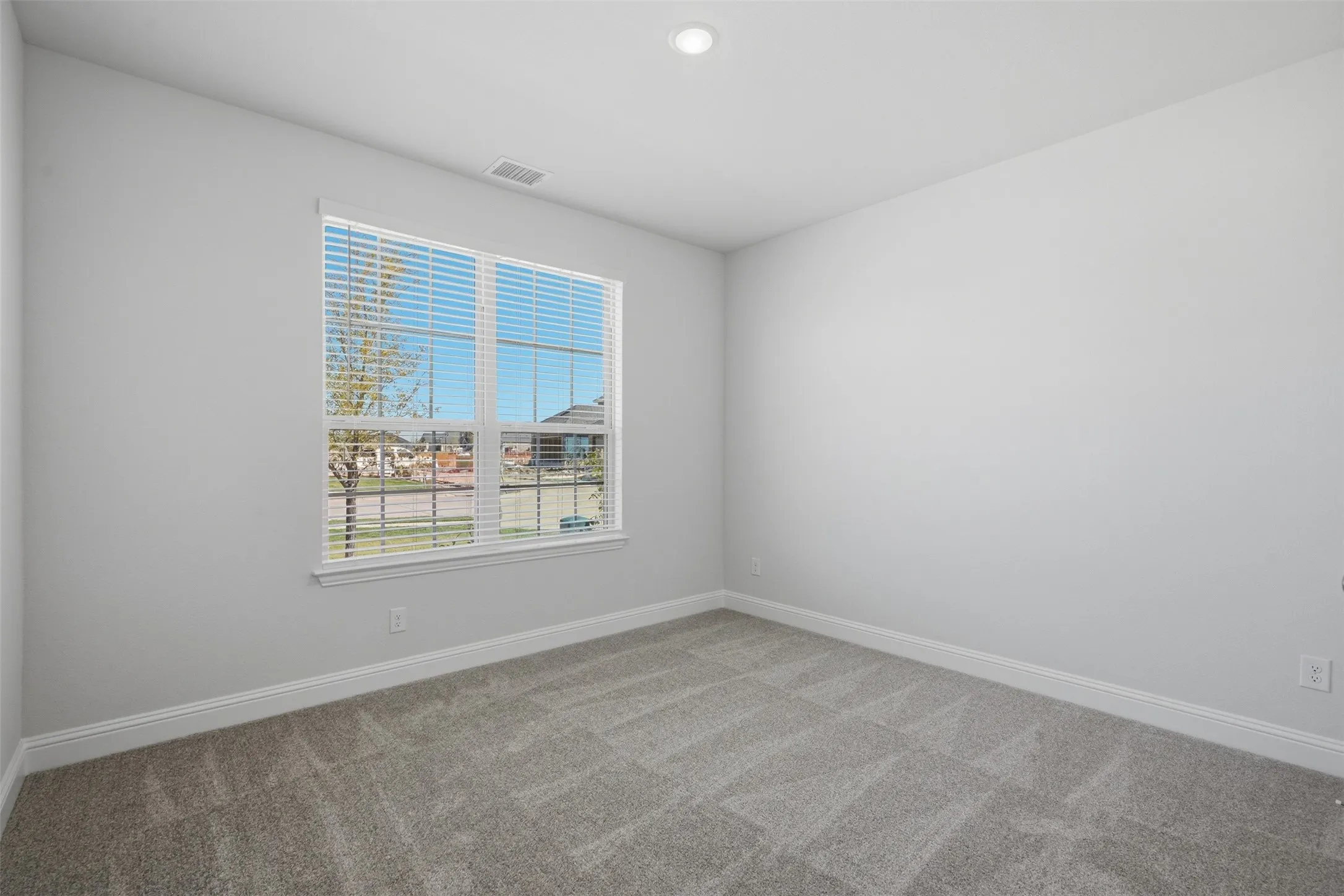 Recessed ceiling light, carpeted flooring, window with blinds, white wall finish, and white trim