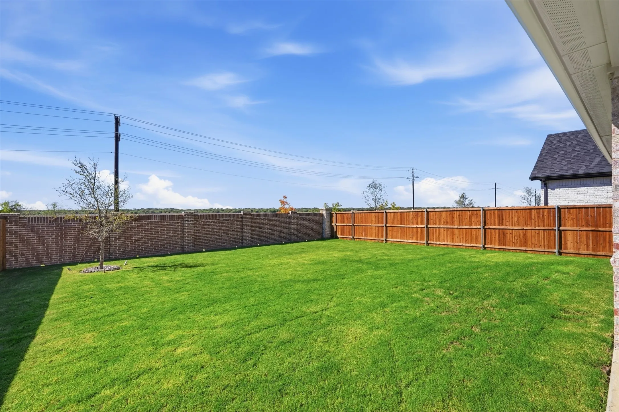 Expansive lawn with a wooden privacy fence and a brick perimeter wall