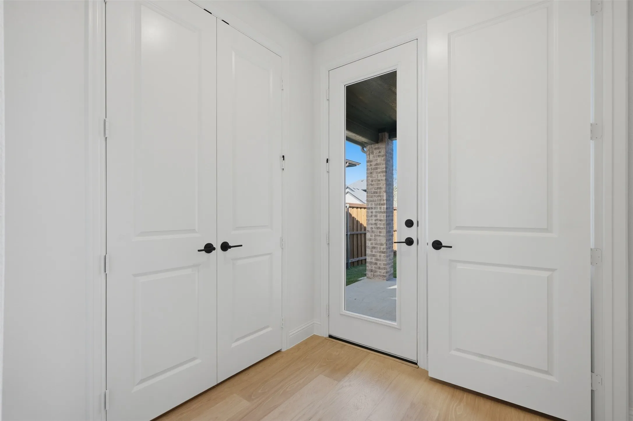Light wood-finish flooring, white paneled doors, and a glass-paneled exterior door