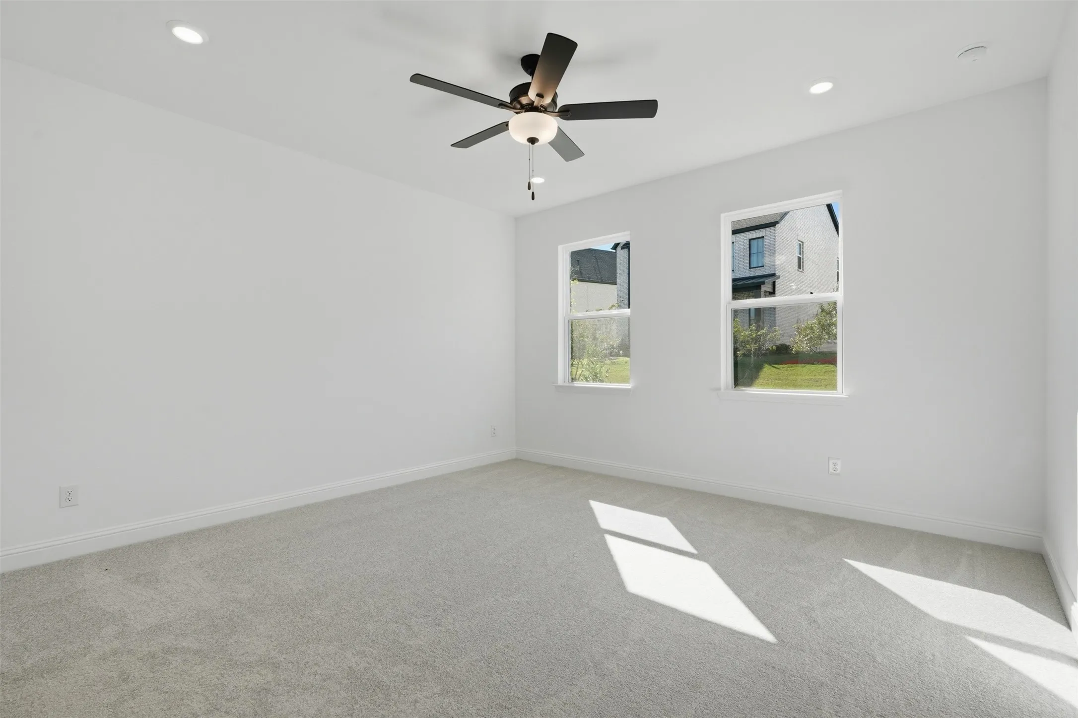 Recessed lighting, ceiling fan with integrated light, two windows, wall-to-wall carpeting, and white painted walls