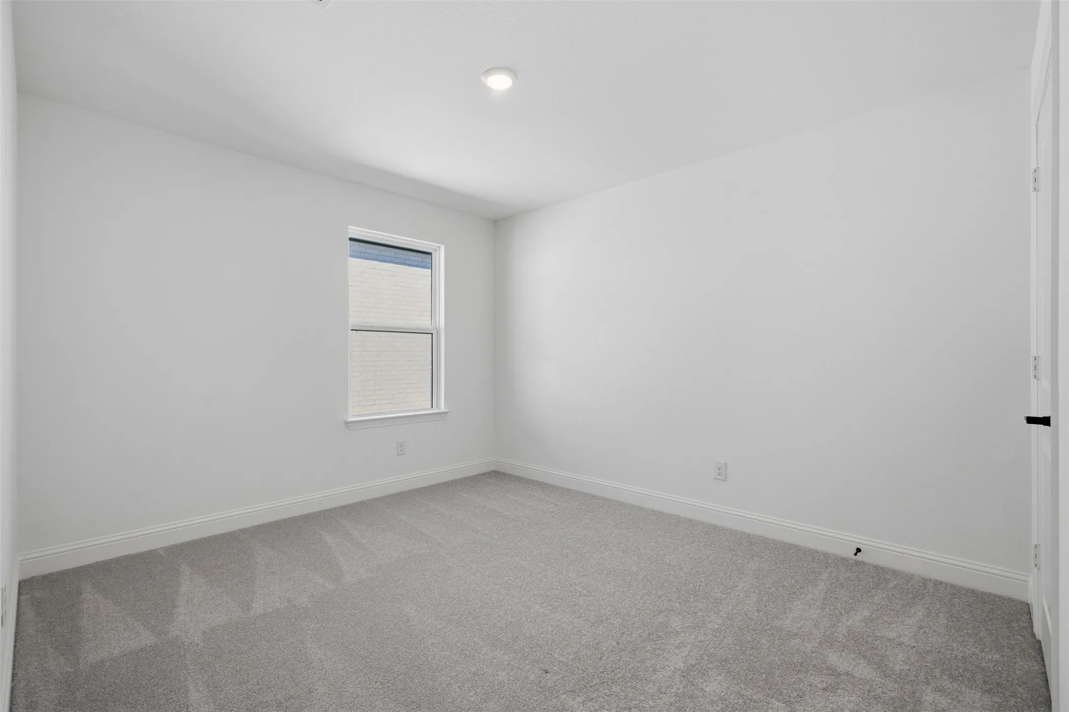 Neutral wall color, recessed ceiling light, window with exterior brick detail, gray carpet, and baseboard molding