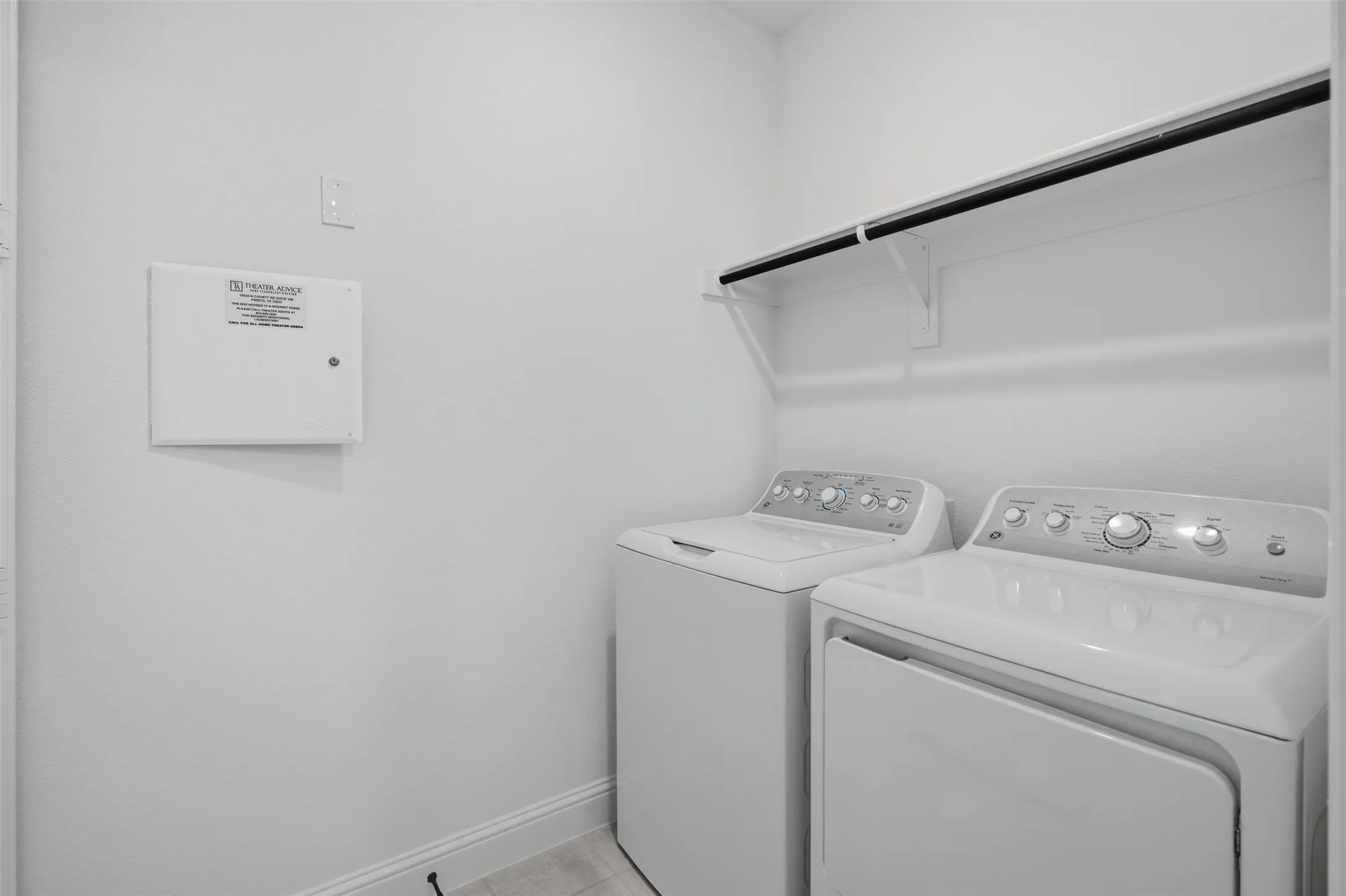 Laundry area with white walls, a built-in shelf, and a clothing rod