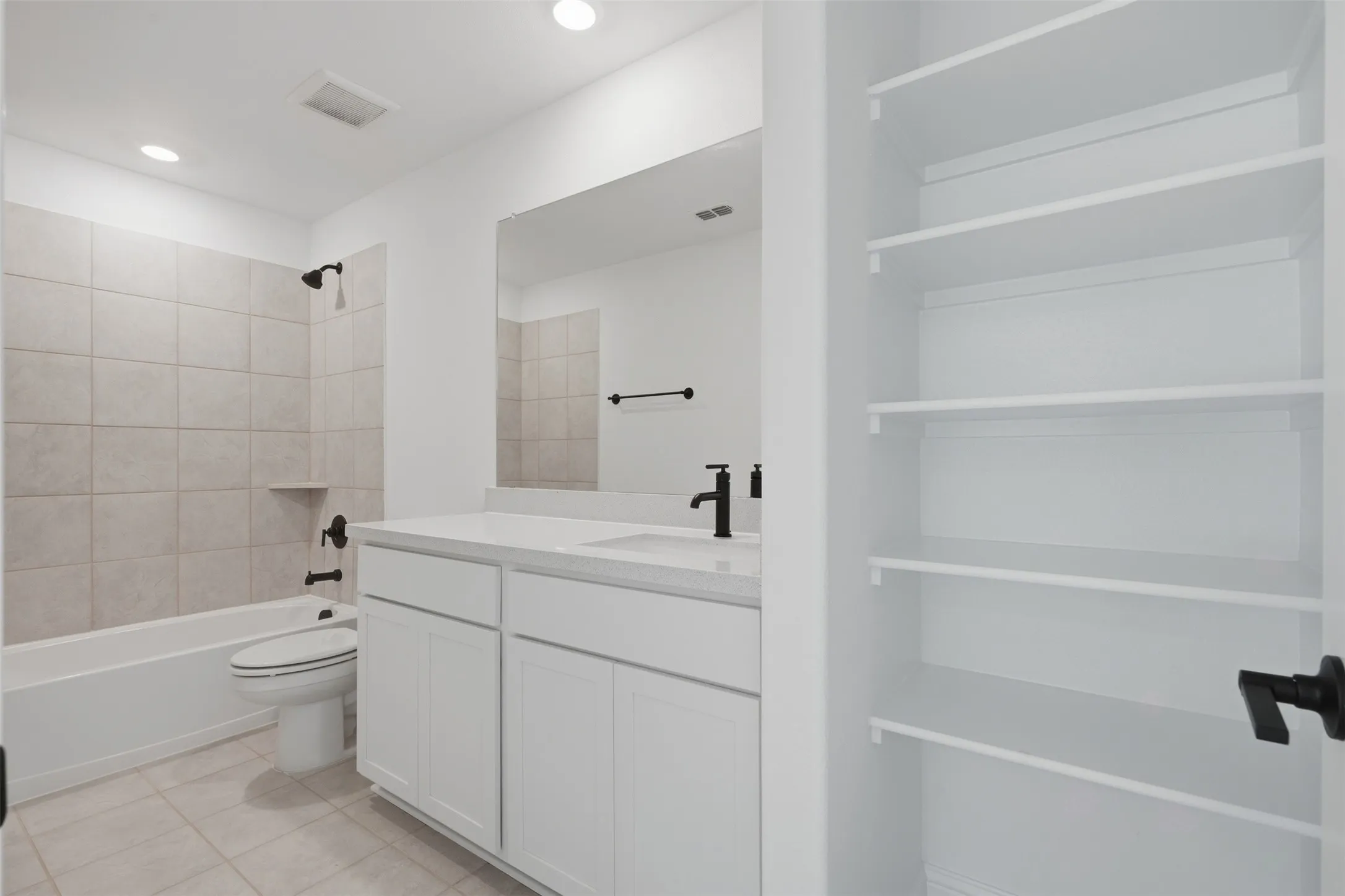 White cabinetry with a white countertop and rectangular sink, matte black fixtures, tile flooring, built-in shelving, and a tiled shower-tub combination