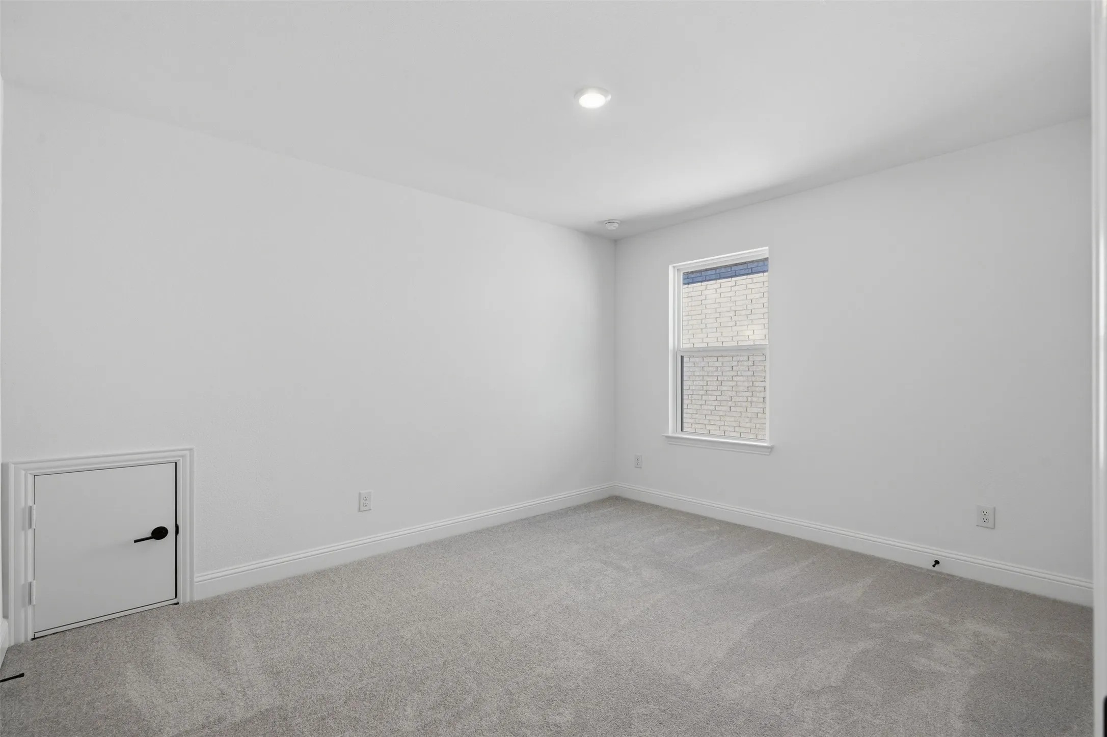 Recessed lighting, white walls, gray carpeting, a single window, and a built-in access panel