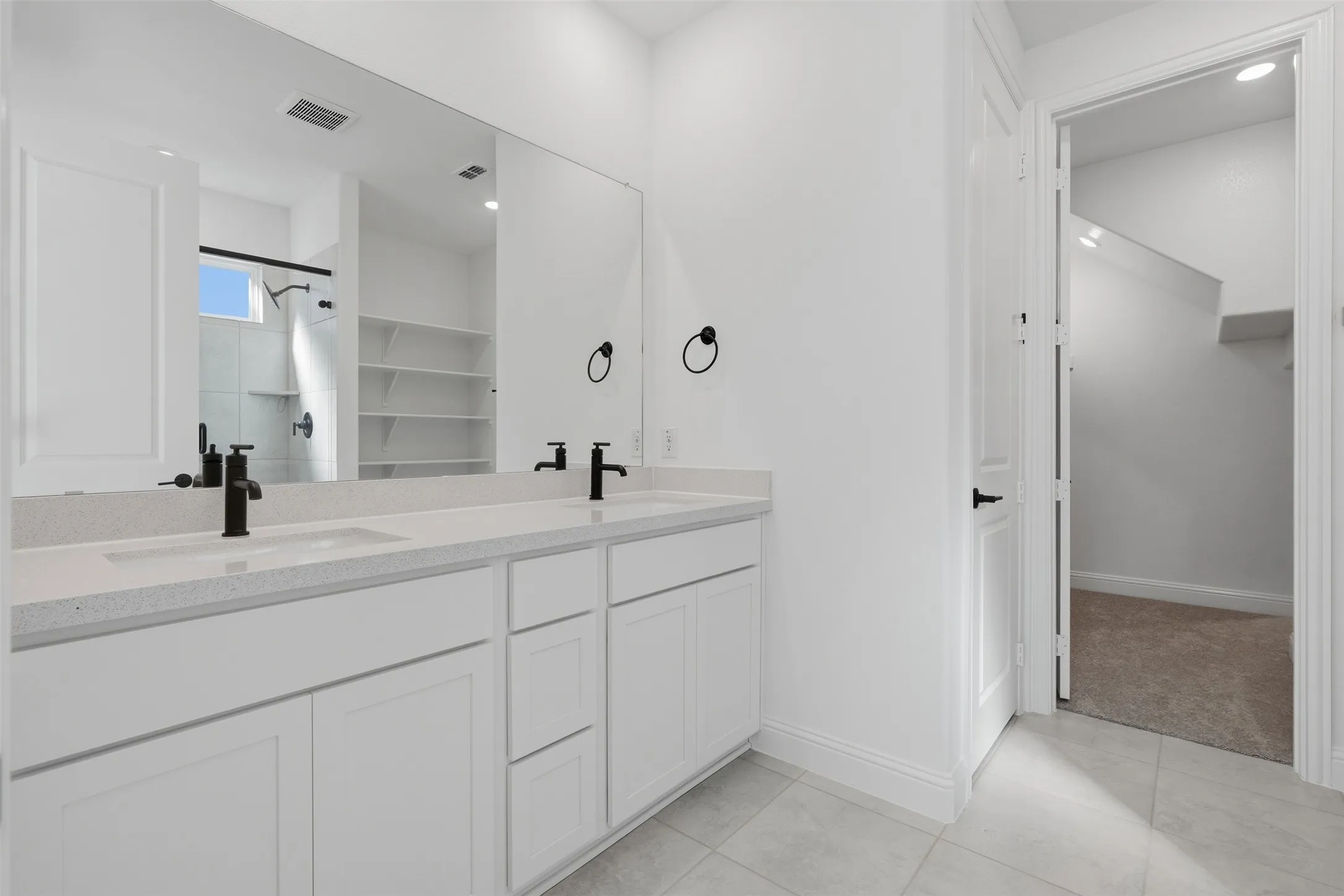 Dual vanity with white cabinetry, light-toned countertop, and matte black fixtures