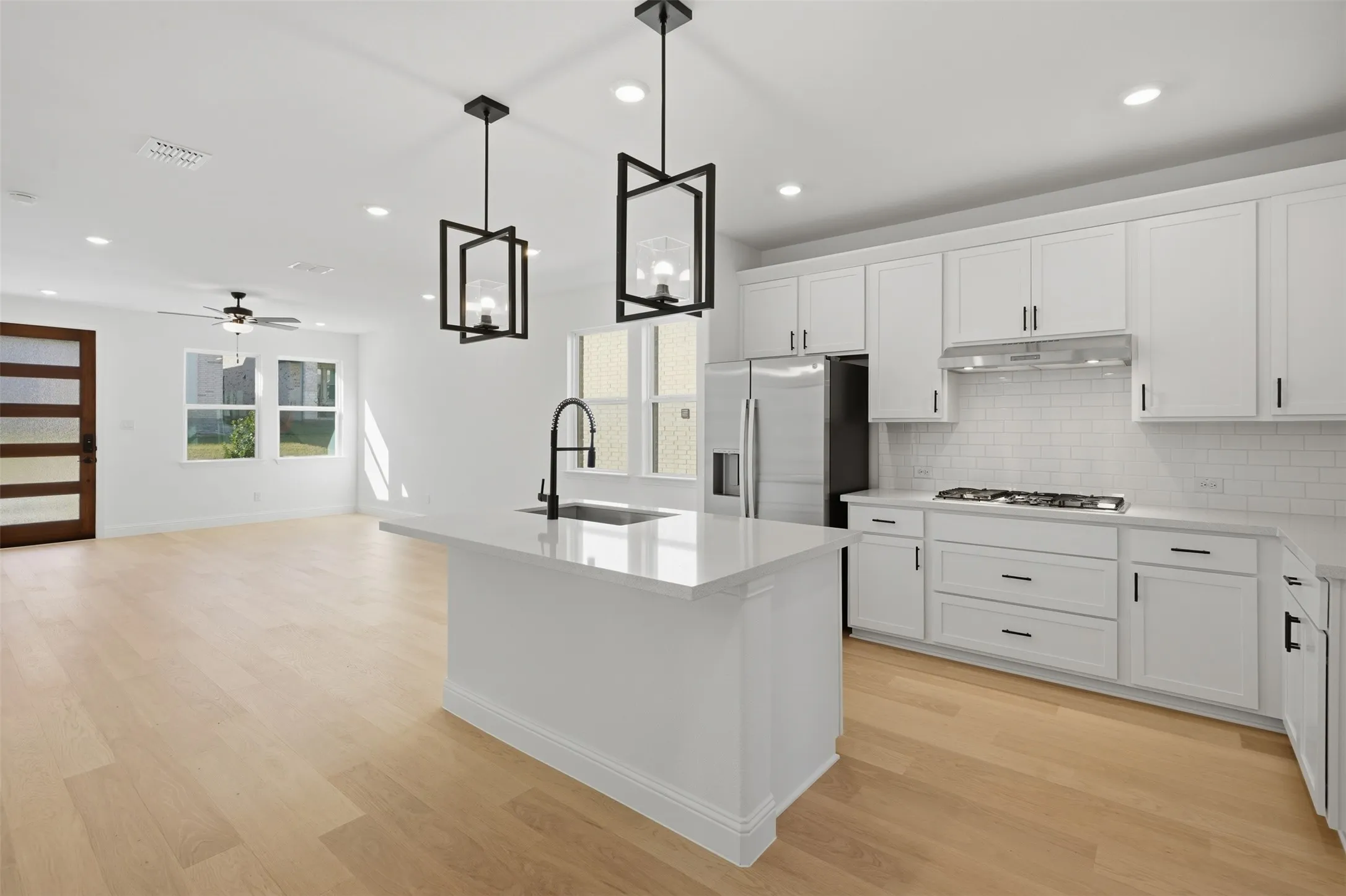 Kitchen featuring white cabinetry, subway tile backsplash, stainless steel appliances, and a central island with a sink